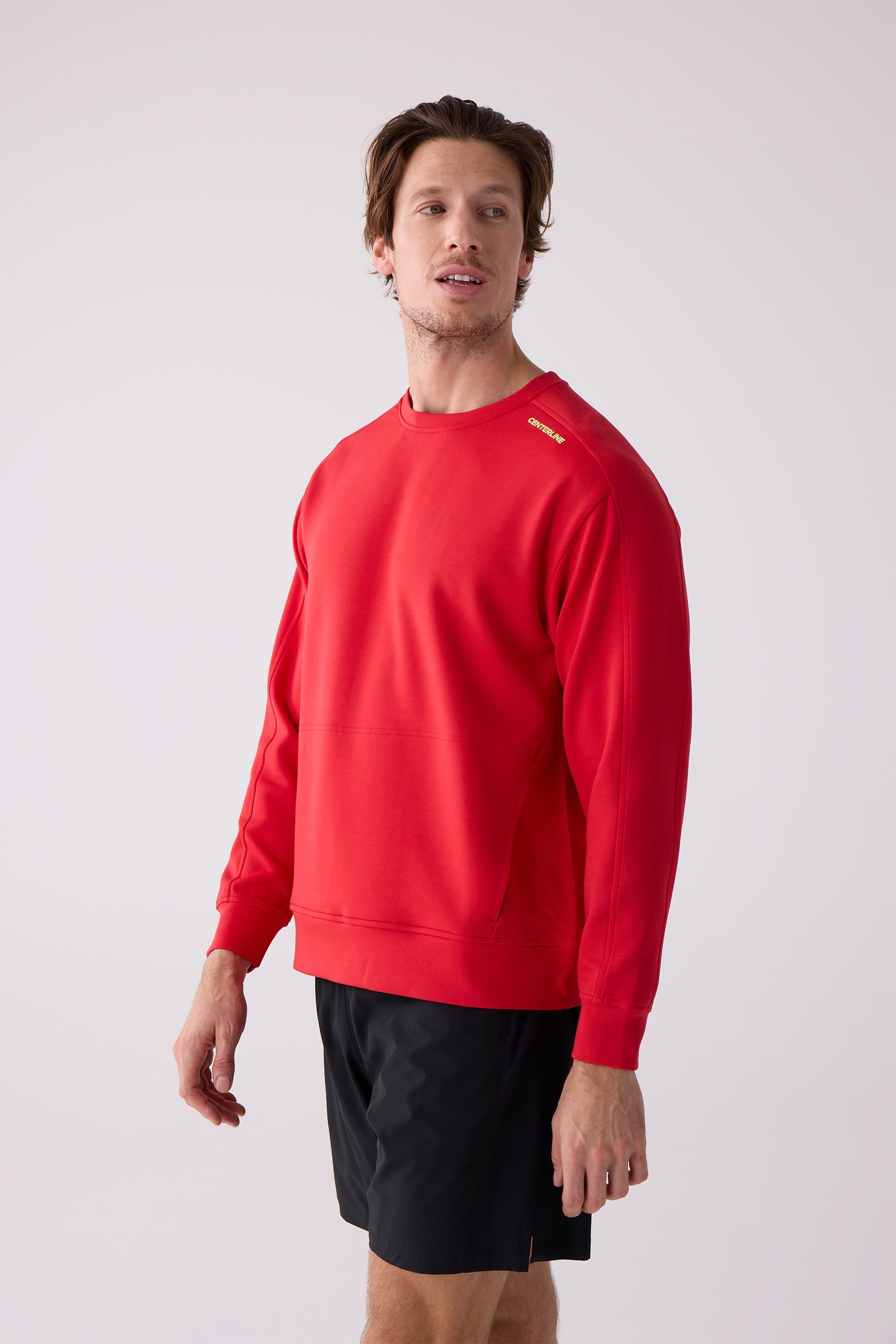 Red Men's Crew Sweatshirt by Centerline Athletics, featuring yellow text on the shoulder and a front kangaroo pocket, worn with black shorts.