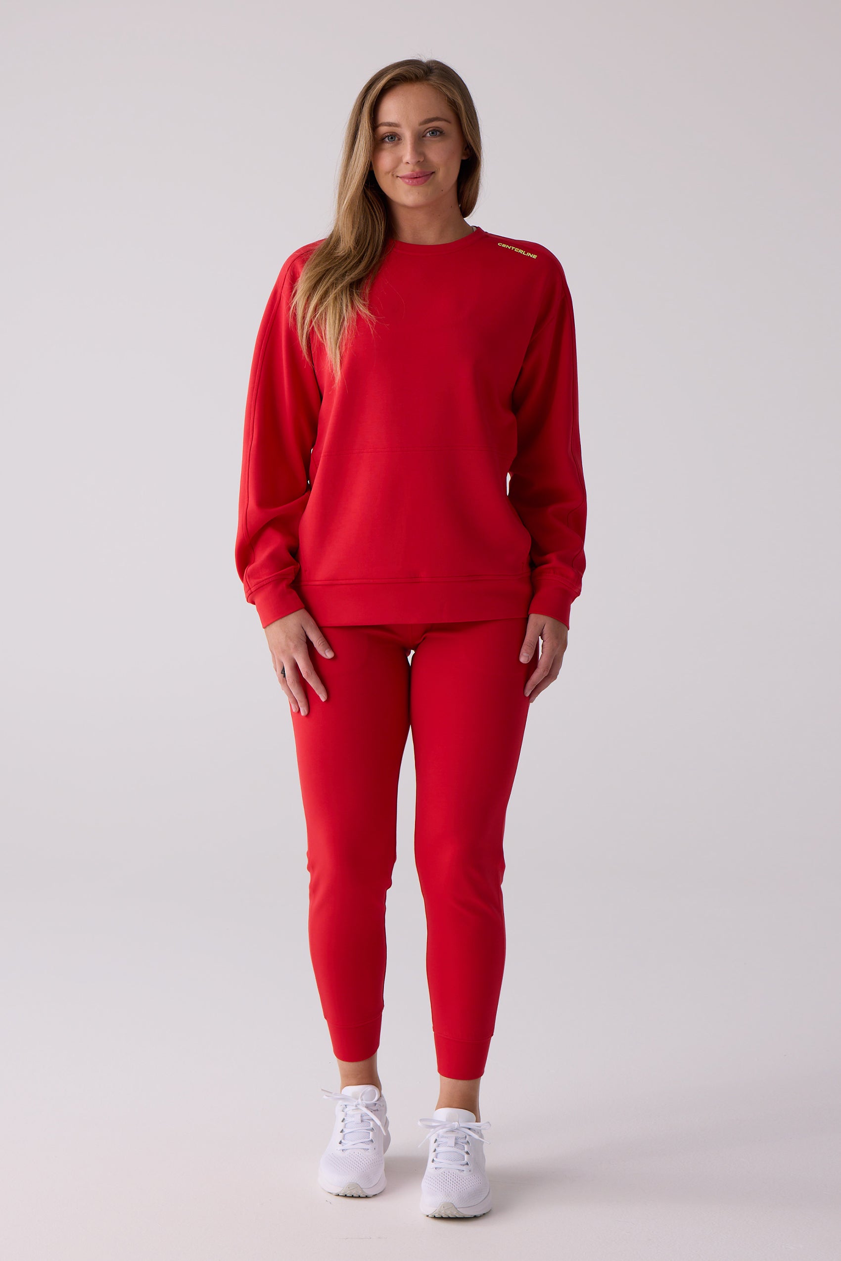 Red crew sweatshirt by Centerline Athletics with yellow "CENTERLINE" lettering on the right shoulder, paired with red sweatpants and white sneakers.