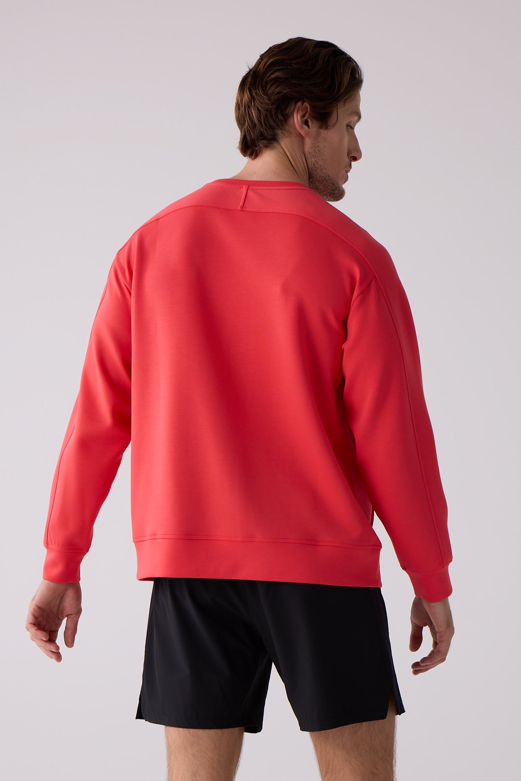 Coral men's crew sweatshirt by Centerline Athletics, back view with ribbed cuffs and hem, styled with black shorts.