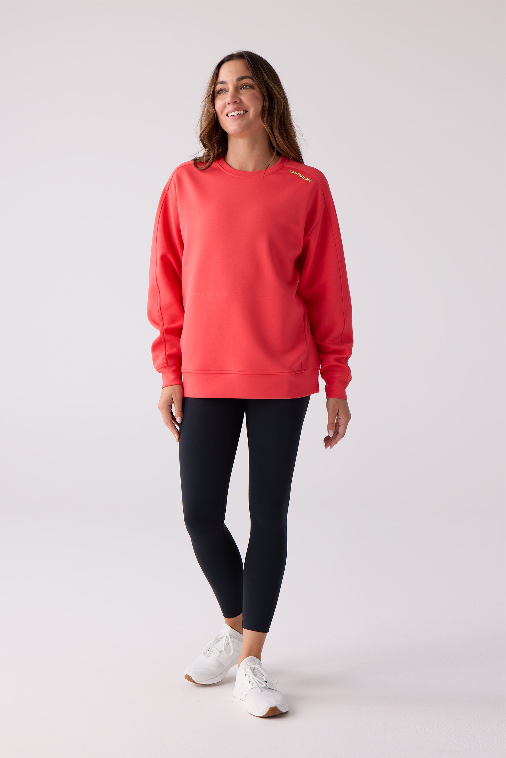 Coral red women's crew sweatshirt by Centerline Athletics with "CENTERLINE" text on shoulder, worn with black leggings and white sneakers.