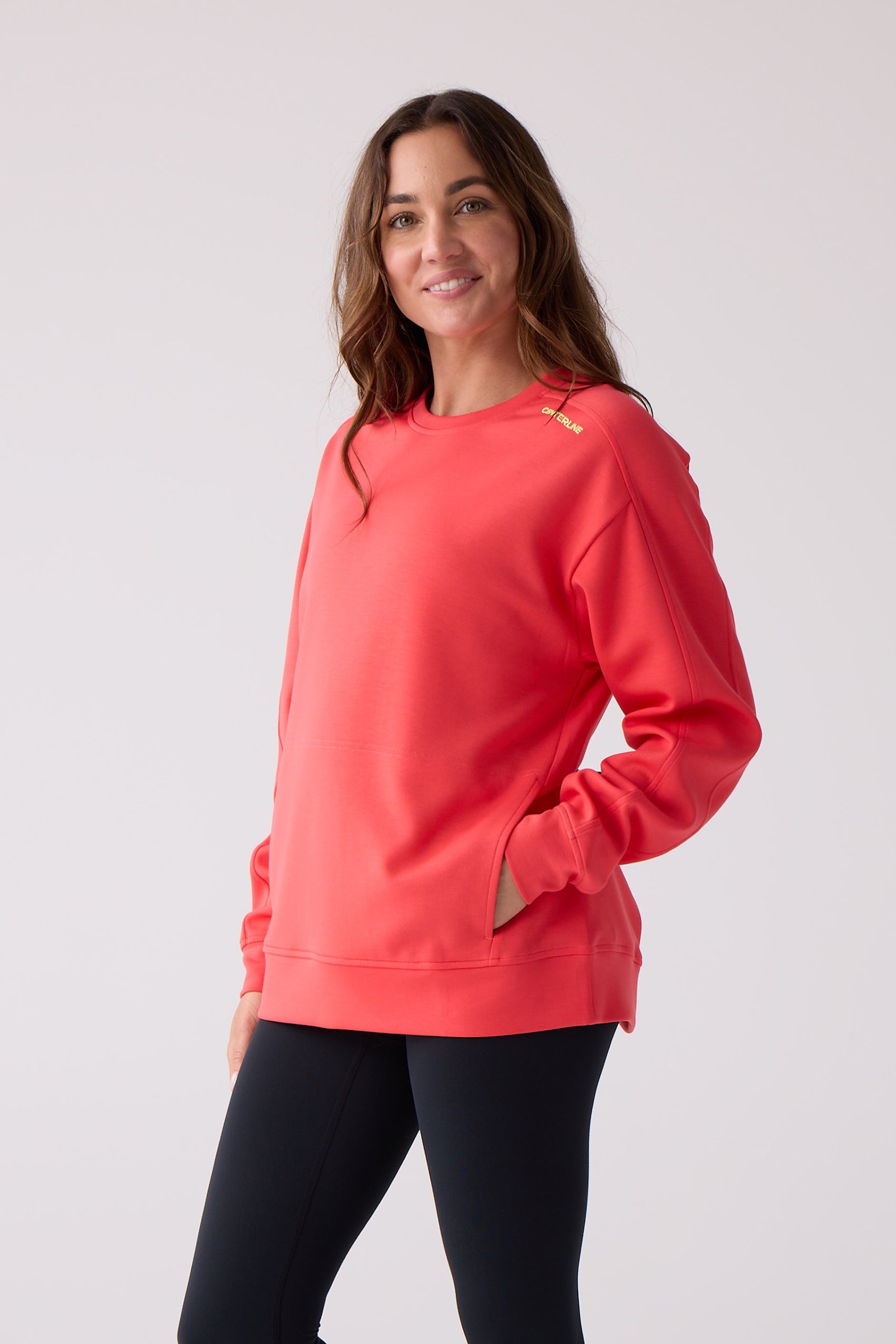 Coral crew sweatshirt by Centerline Athletics with yellow 'CENTERLINE' text on the shoulder and side pockets, paired with black leggings.