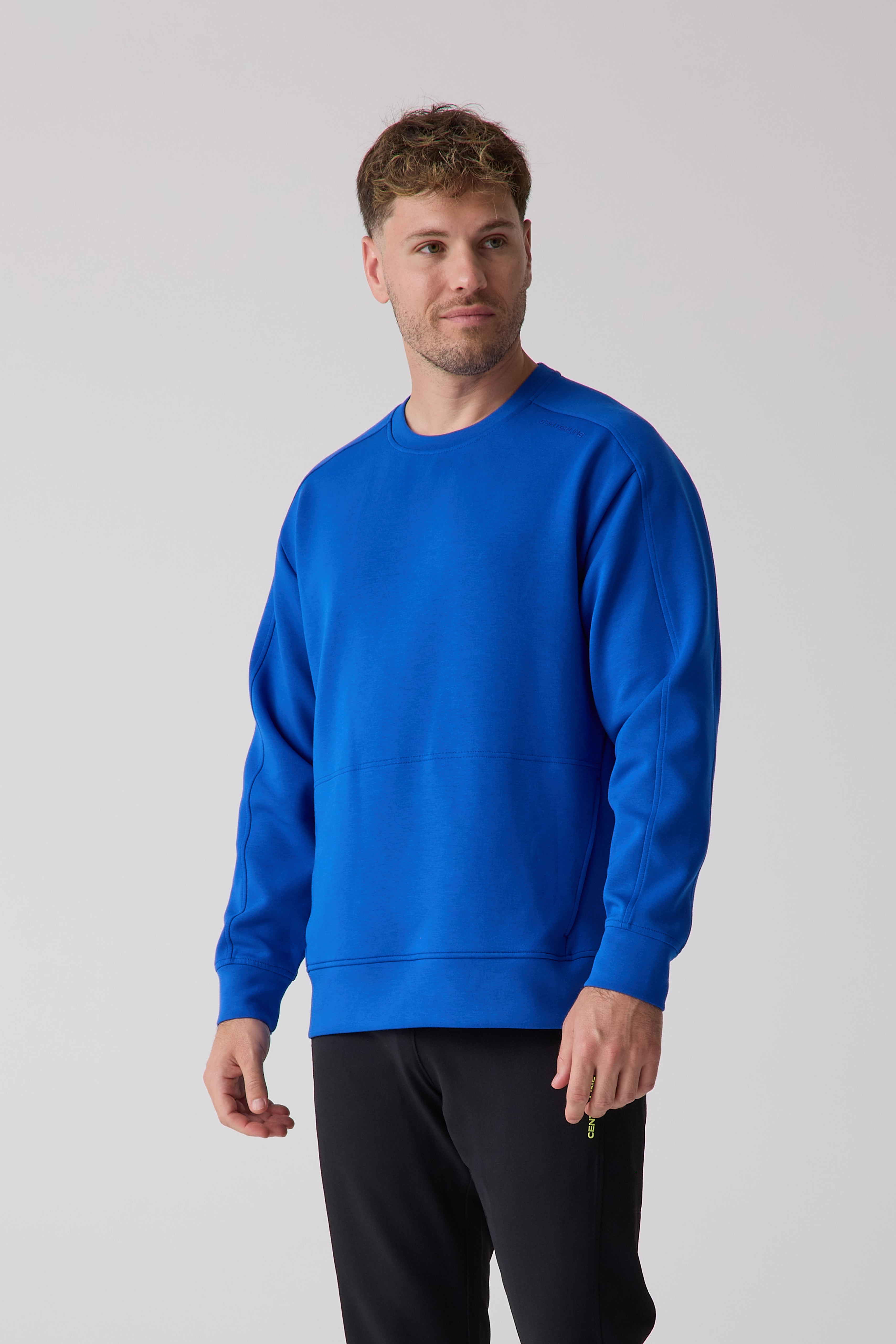 Blue men's crew sweatshirt by Centerline Athletics, with distinct seam details and shoulder branding, worn by a male model in black pants.