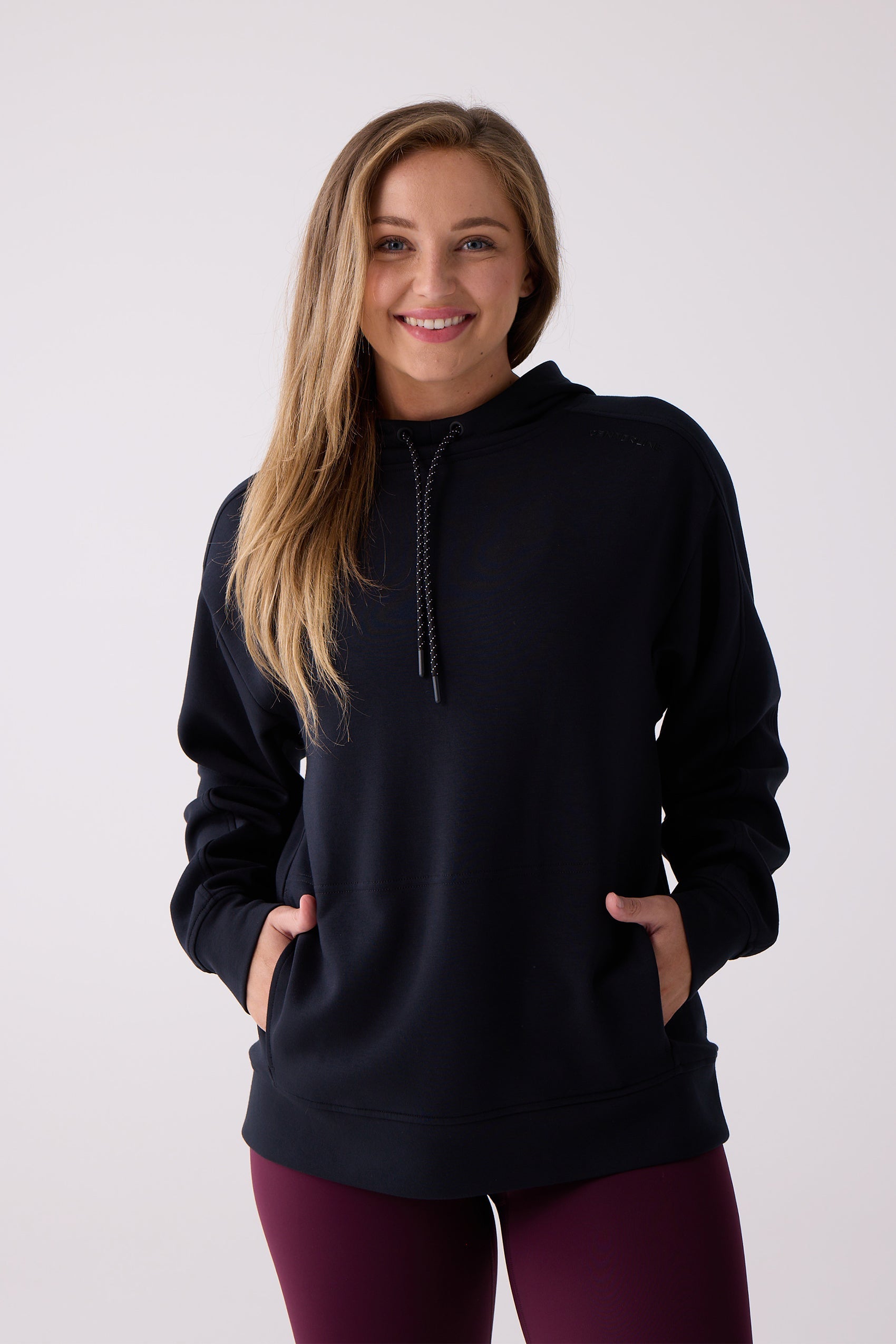 Black hooded sweatshirt by Centerline Athletics with speckled drawstrings, subtle shoulder logo, and a kangaroo pocket, worn with burgundy leggings.
