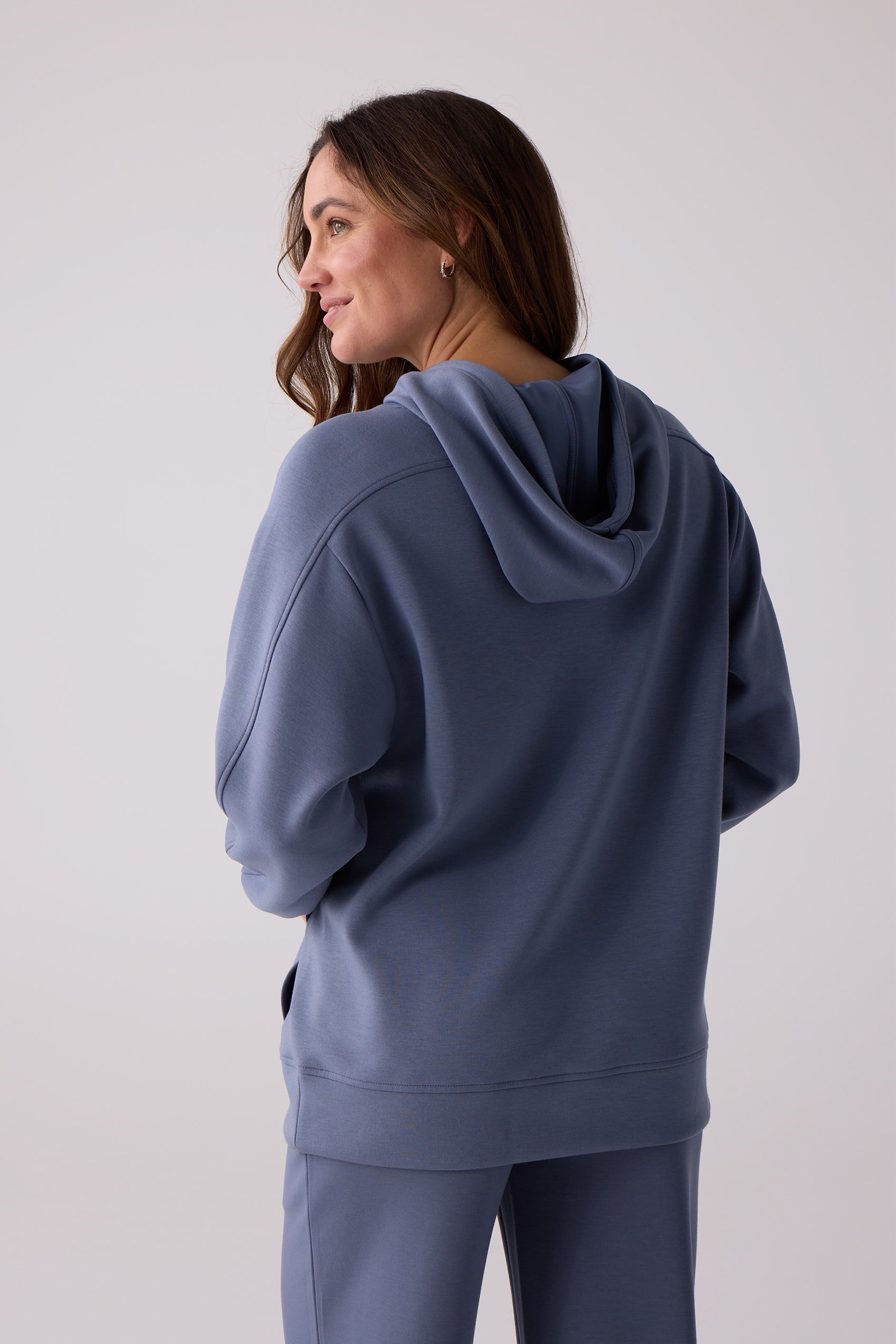 Blue hooded sweatshirt by Centerline Athletics, worn by a woman facing away, with matching pants.