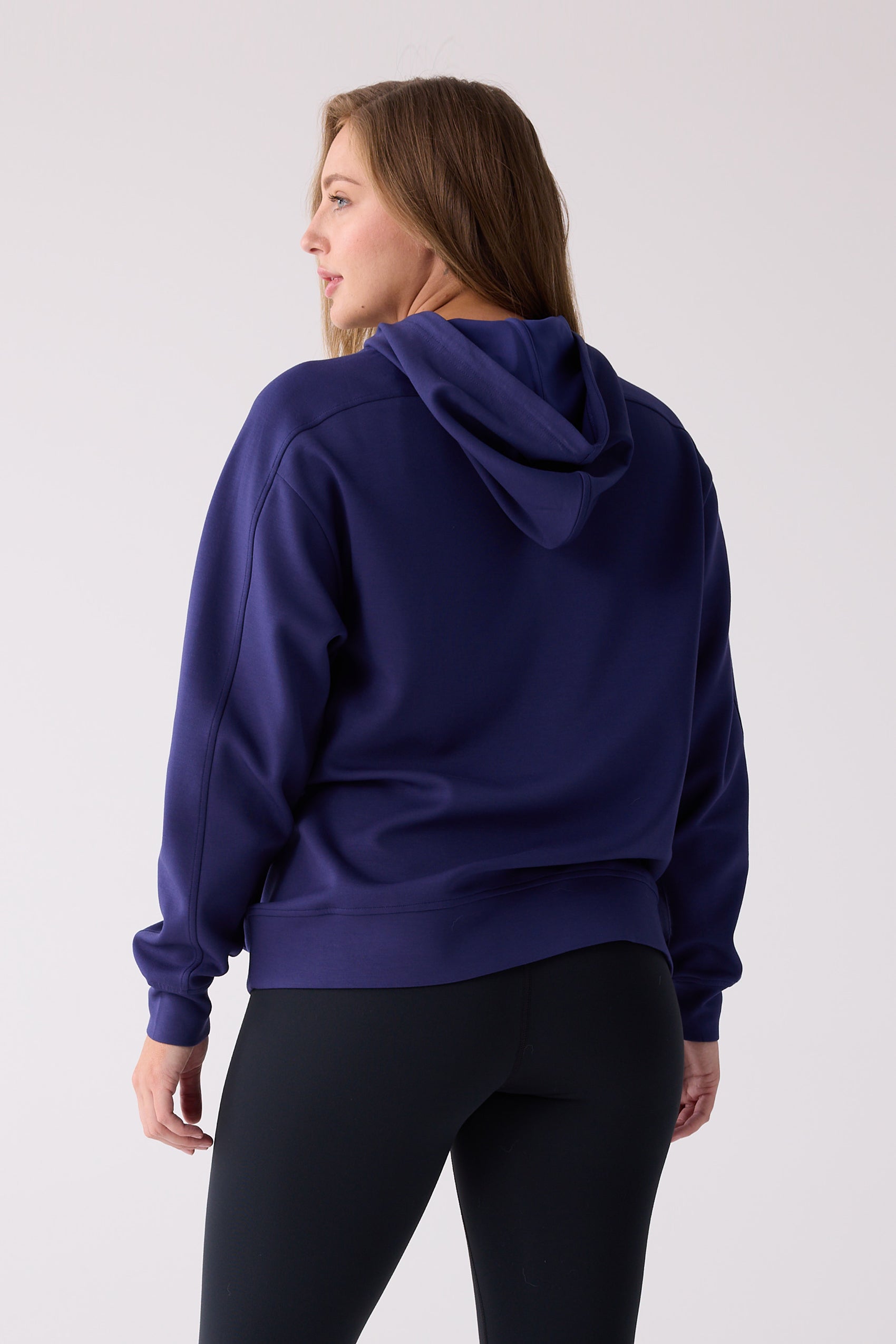 Dark purple hooded sweatshirt by Centerline Athletics, seen from the back on a woman wearing black leggings.