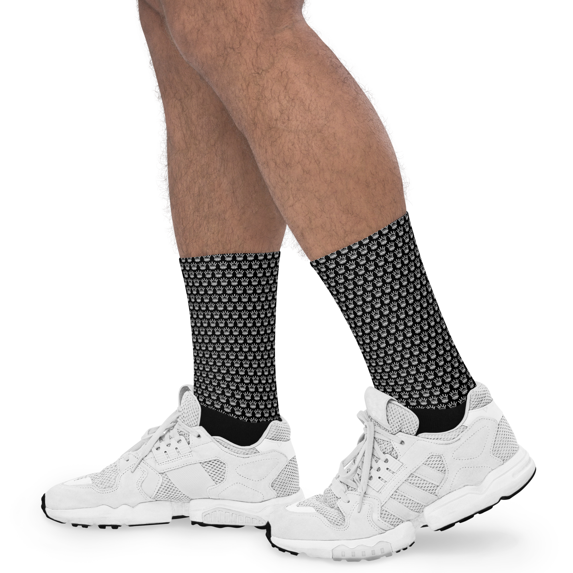 Person wearing black socks with white crown pattern and white sneakers.