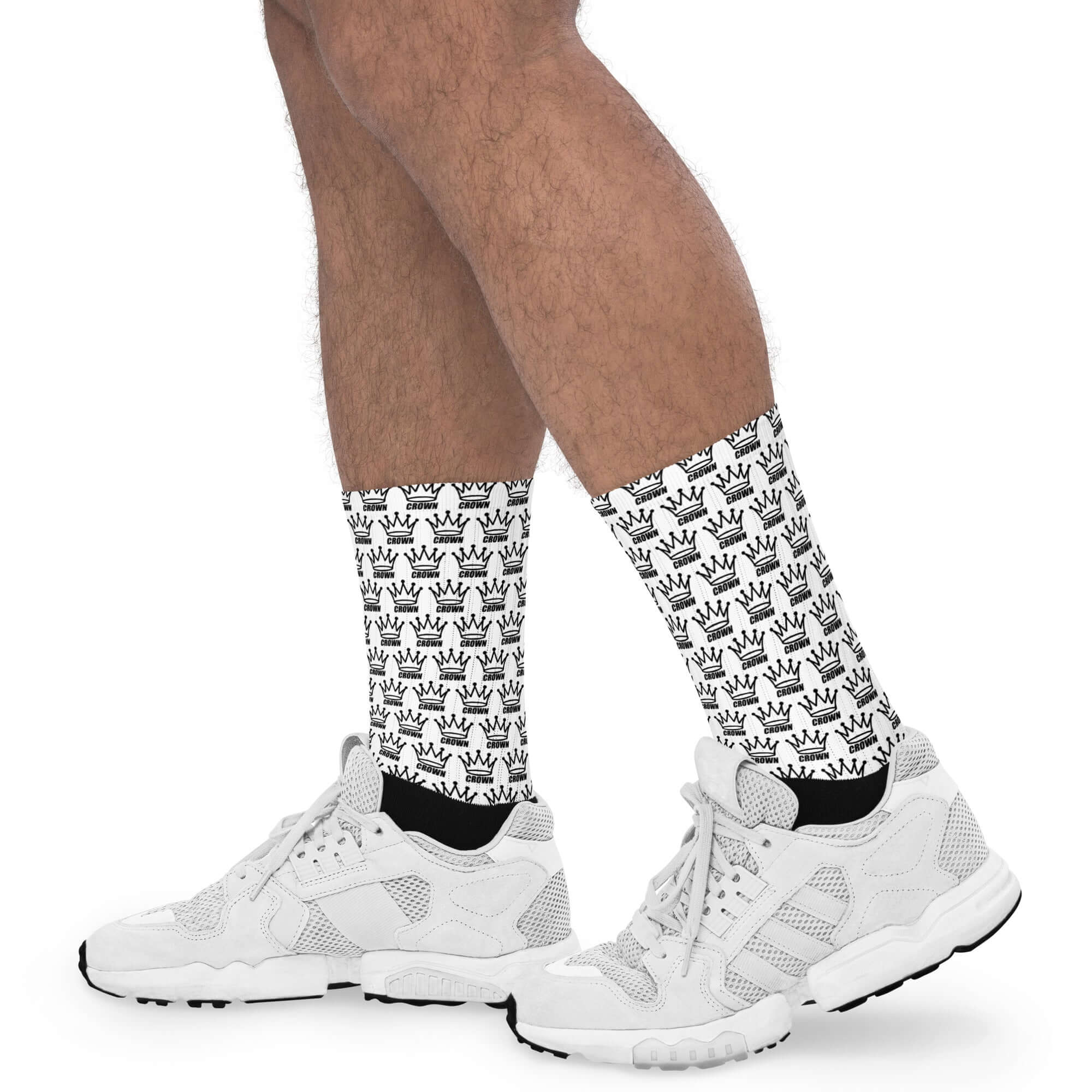 A person wearing white crown-patterned socks and white sneakers.
