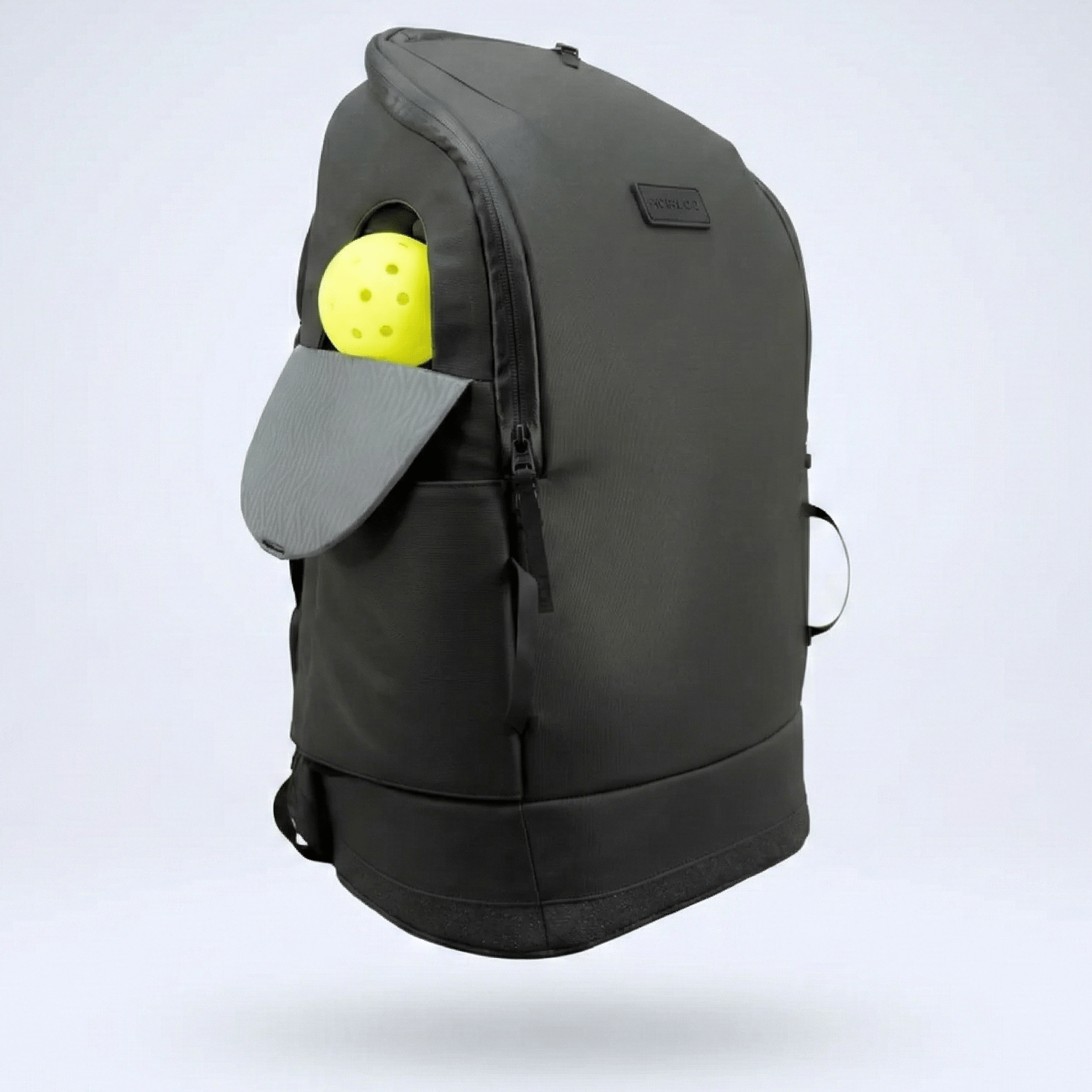 Dark grey pickleball backpack by FORWRD, featuring a yellow pickleball in a side pocket with a grey paddle slot cover, angled.