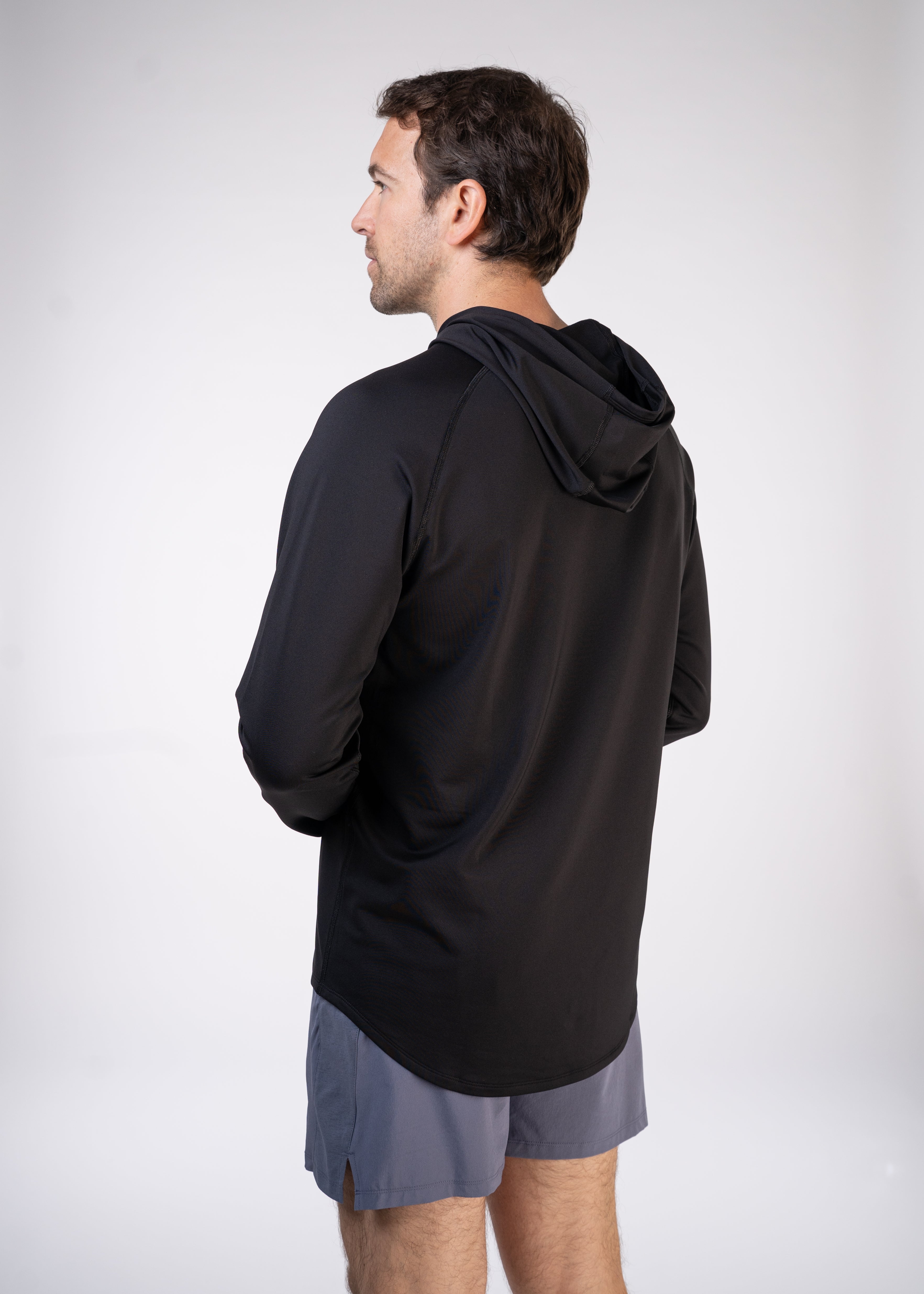 Man wearing a black hooded long-sleeved shirt and gray shorts, facing away from the camera.