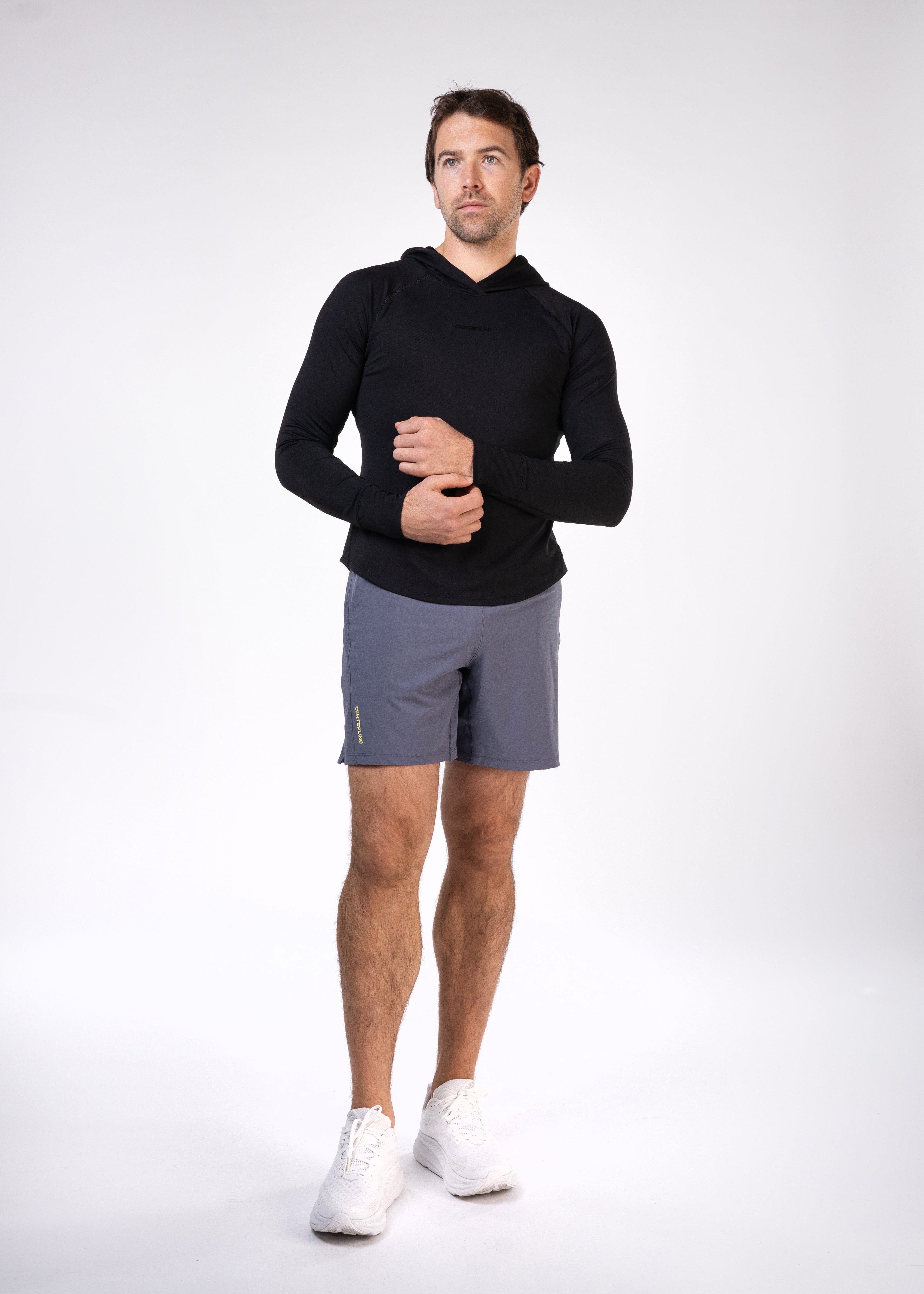Man wearing black hooded shirt, gray shorts, and white shoes.
