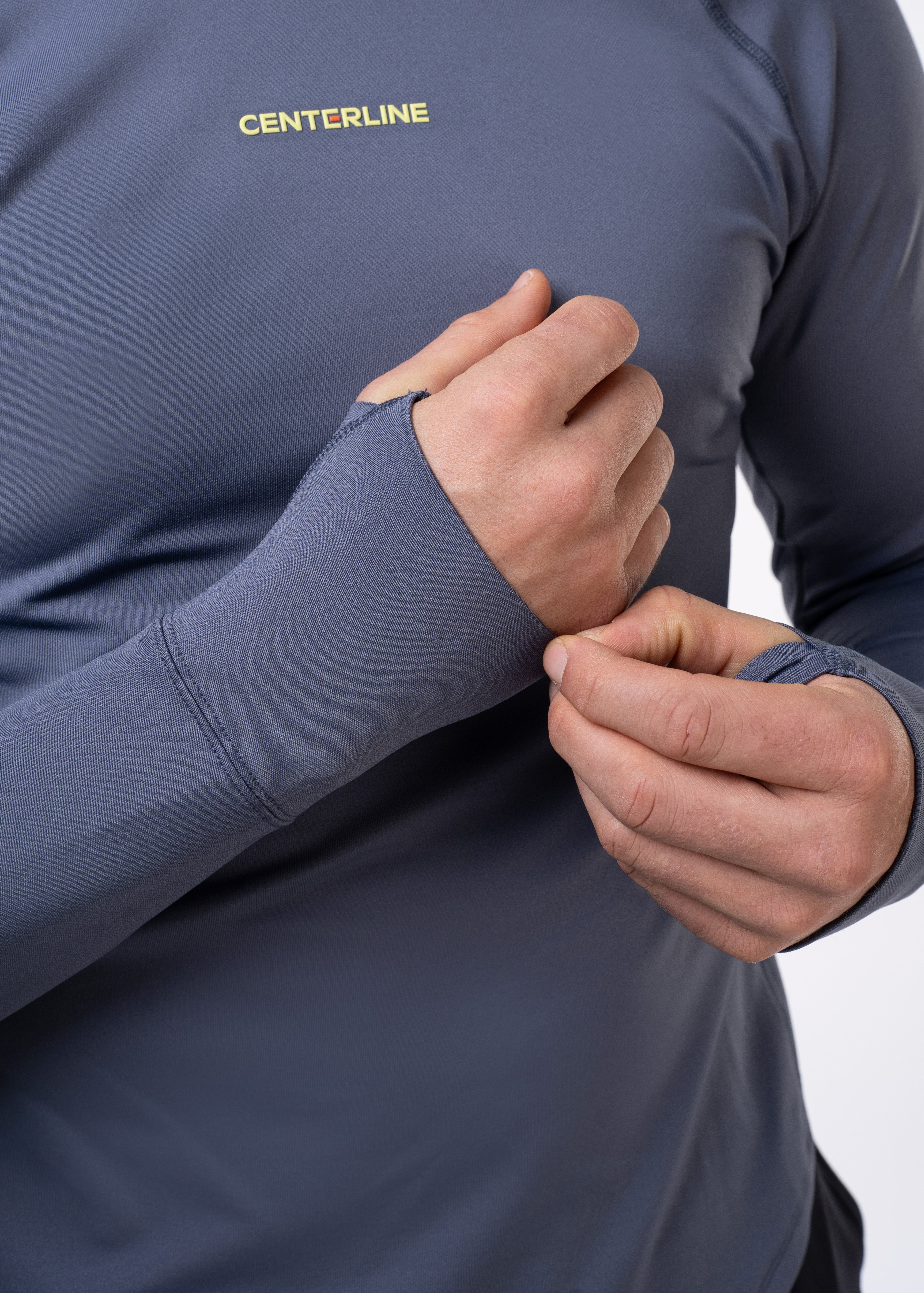 Man adjusting the thumb hole of a gray long-sleeved athletic shirt.