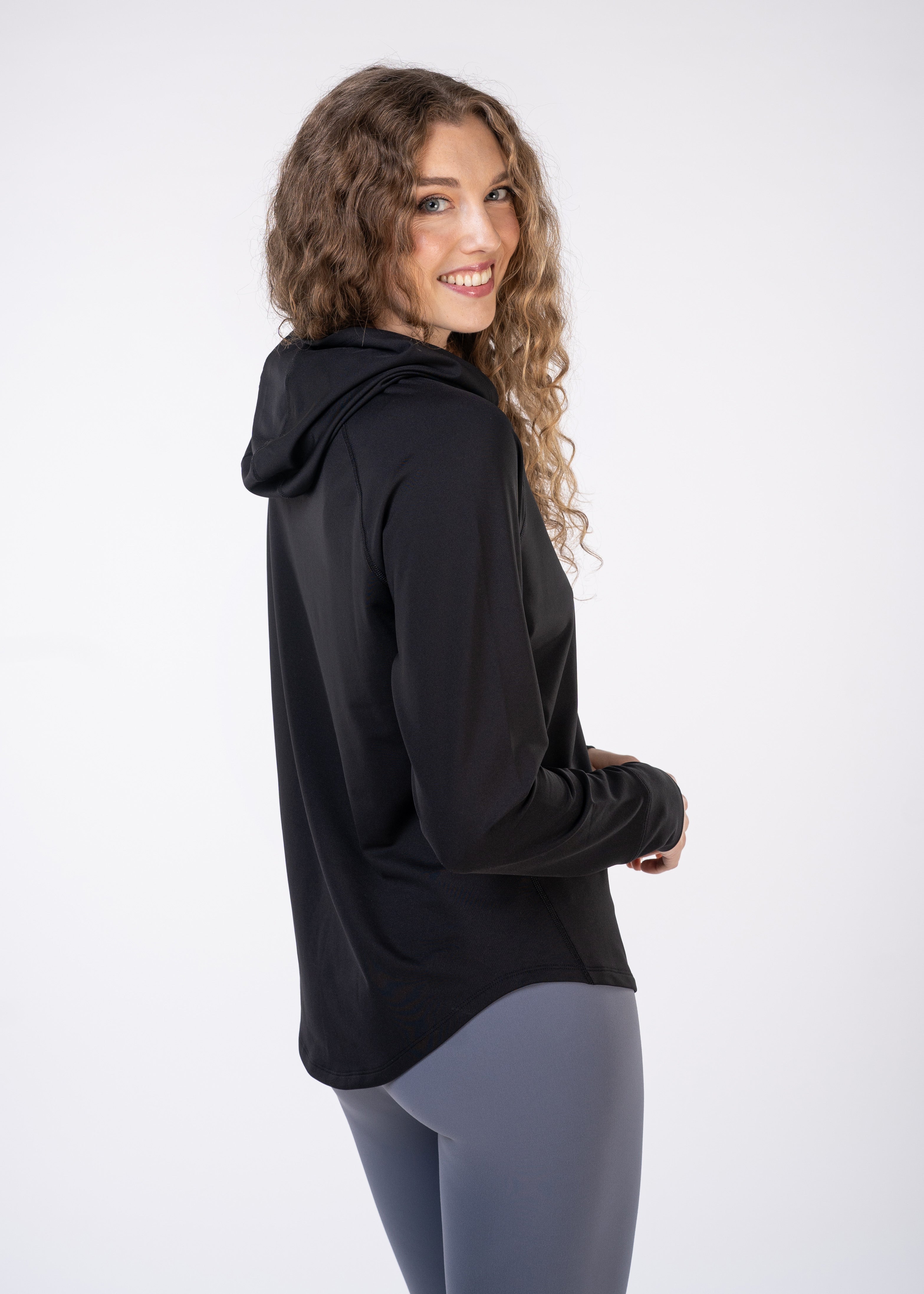 Woman wearing black hooded top and grey leggings.