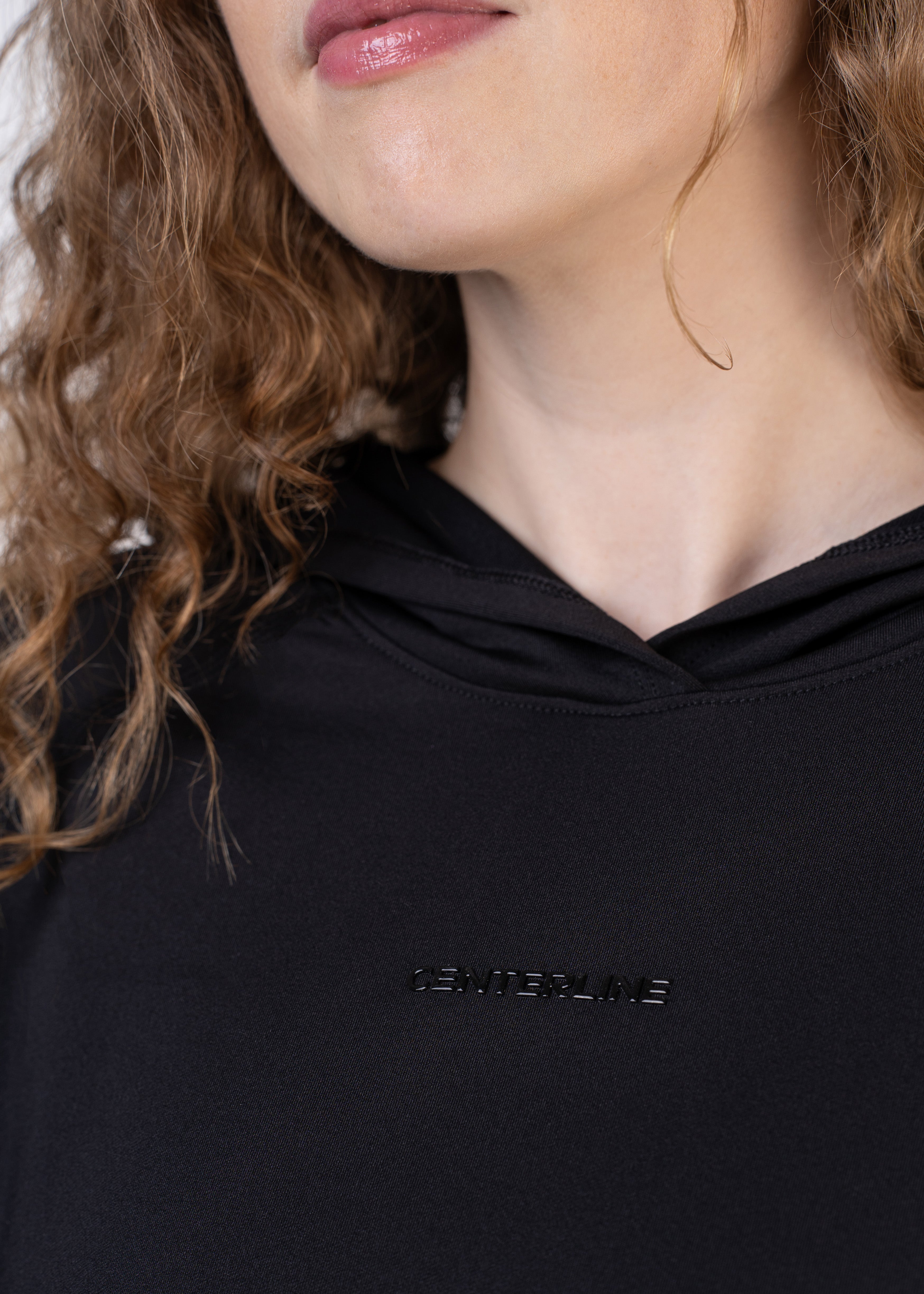 Close-up of a woman's upper chest wearing a black hooded sweatshirt with the word "CENTERLINE" embossed on it.