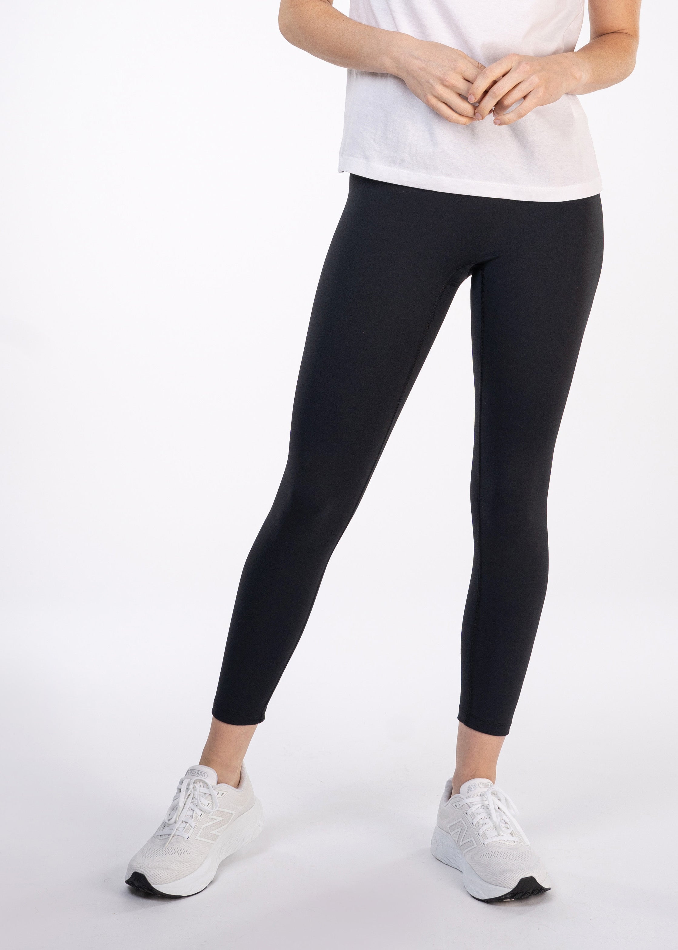 Woman in black leggings, white sneakers, and a white shirt.