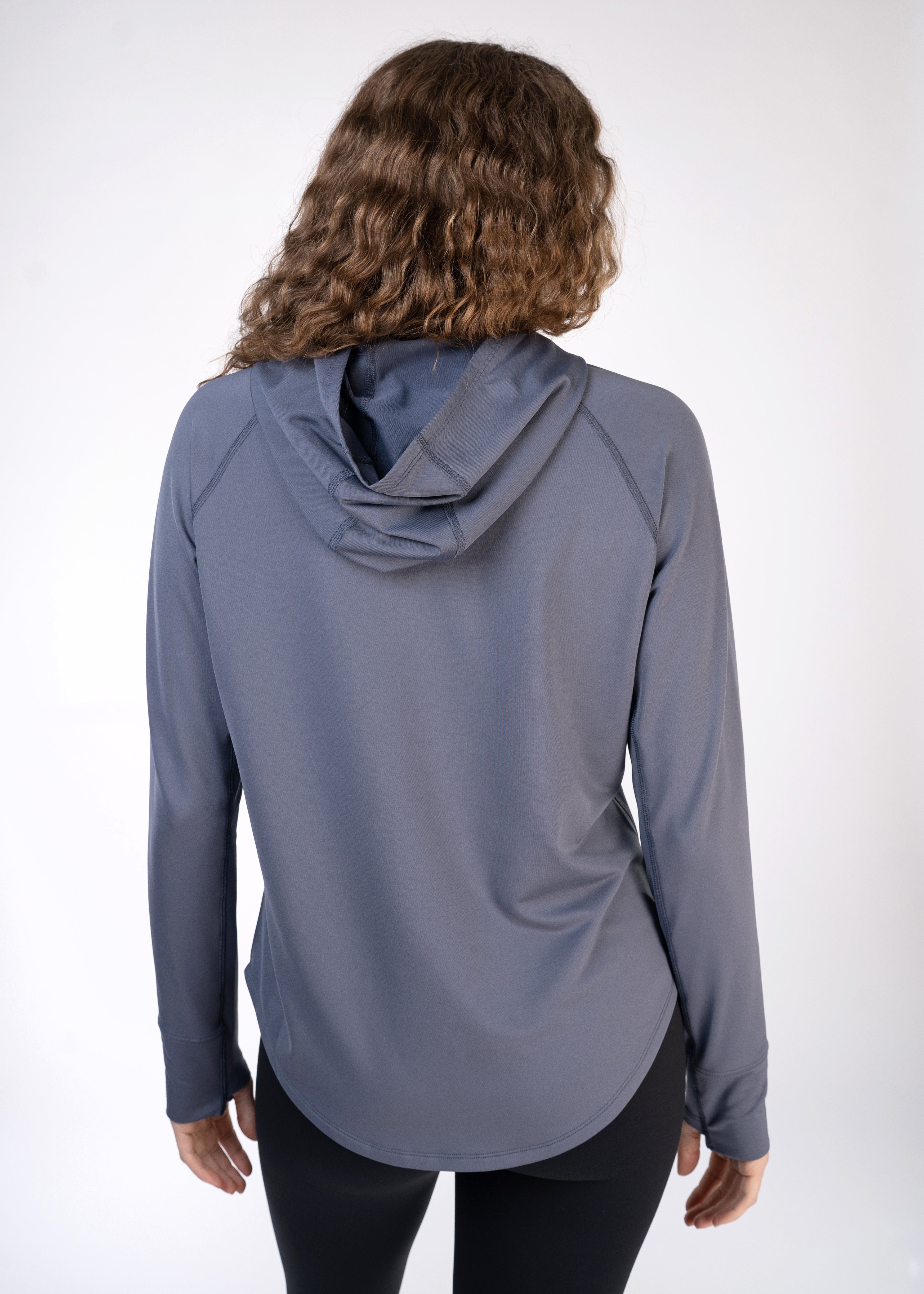 Back view of a woman in a gray long-sleeved hoodie and black leggings.
