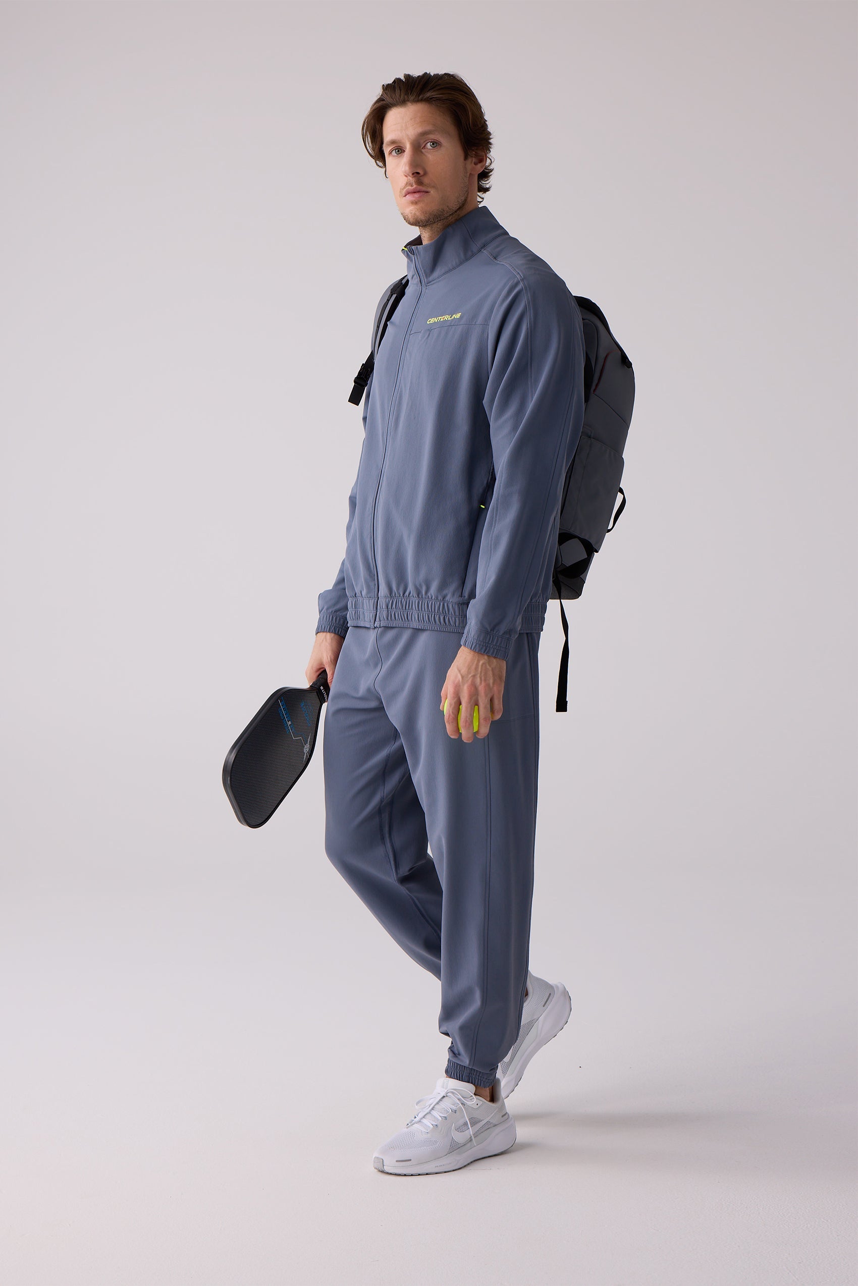 Periwinkle blue Men's Courtside Track Jacket by Centerline Athletics with yellow 'CENTERLINE' chest logo, worn by a man with matching pants.