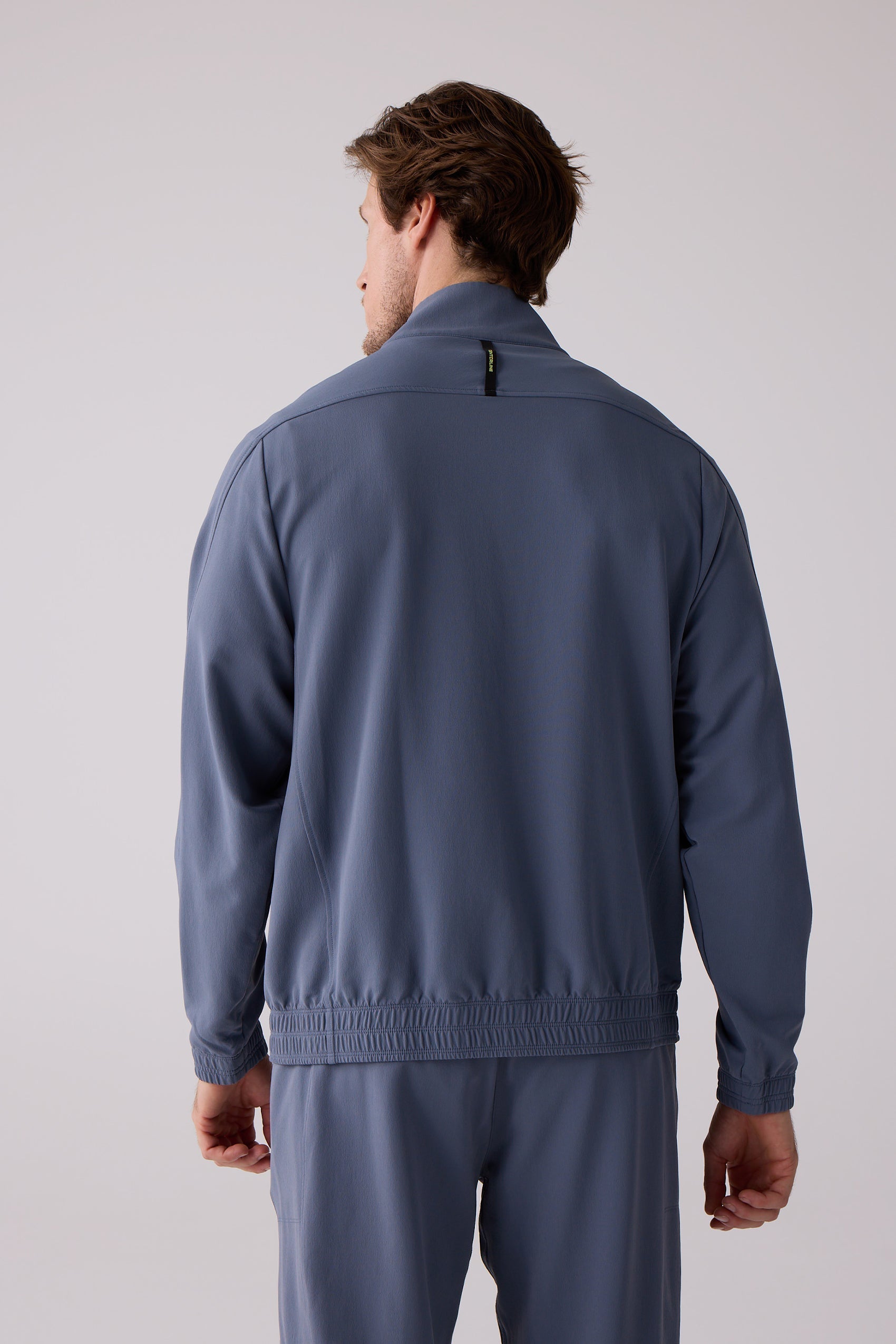 Blue Men's Courtside Track Jacket by Centerline Athletics, back view, with stand-up collar and ribbed details.