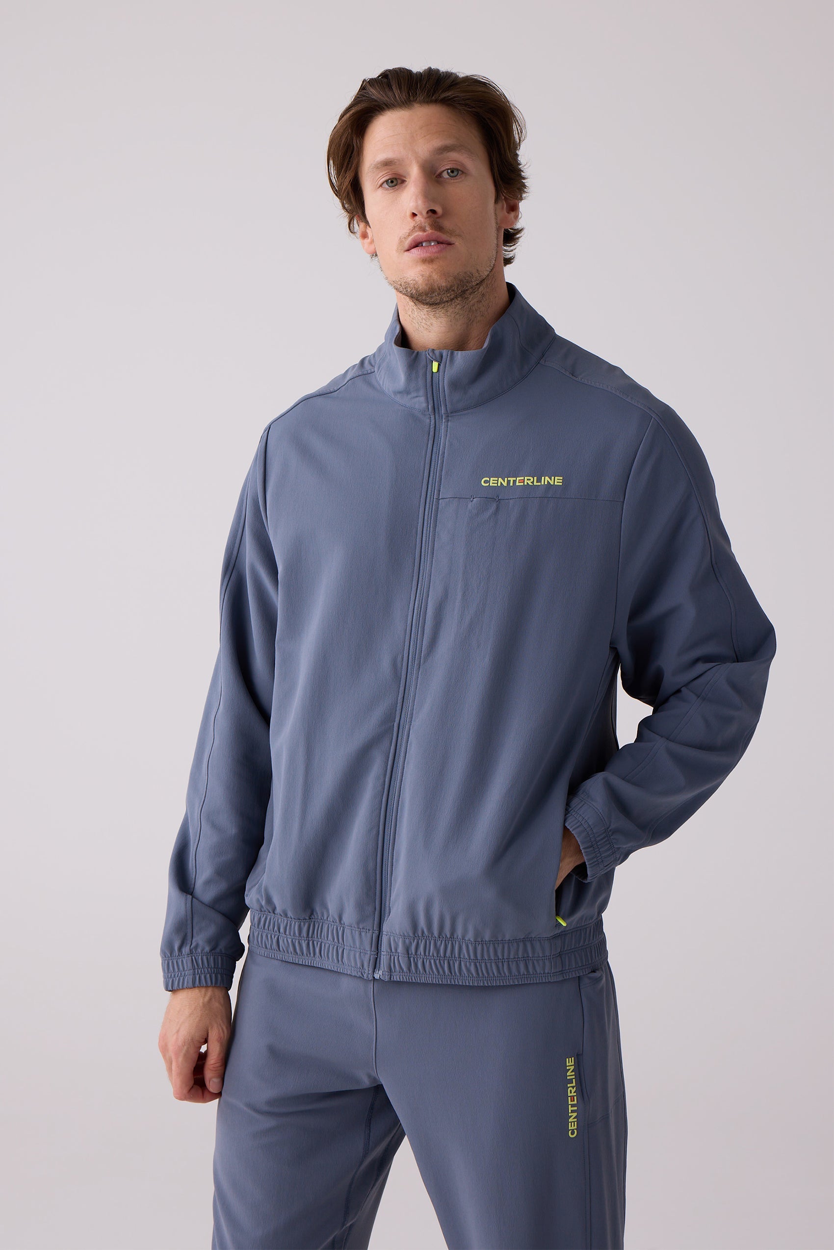 Men's blue full-zip track jacket by Centerline Athletics with a neon yellow chest logo and matching pants.