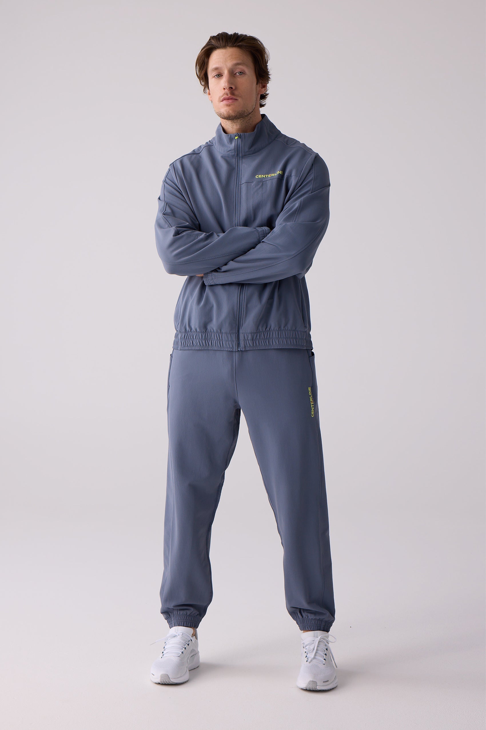 Blue-grey Men's Courtside Track Pants by Centerline Athletics with "CENTERLINE" text, worn with a matching jacket and white sneakers.