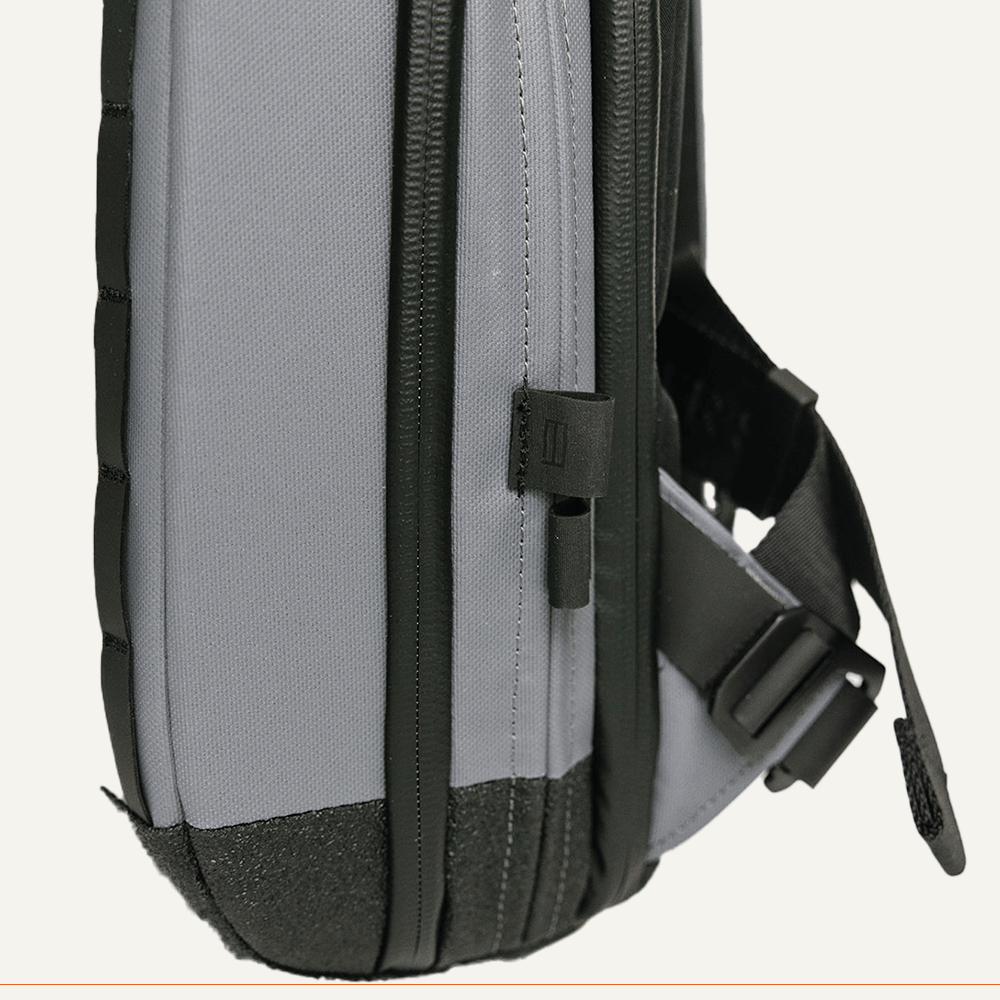 Close-up of gray backpack with black straps and trim.