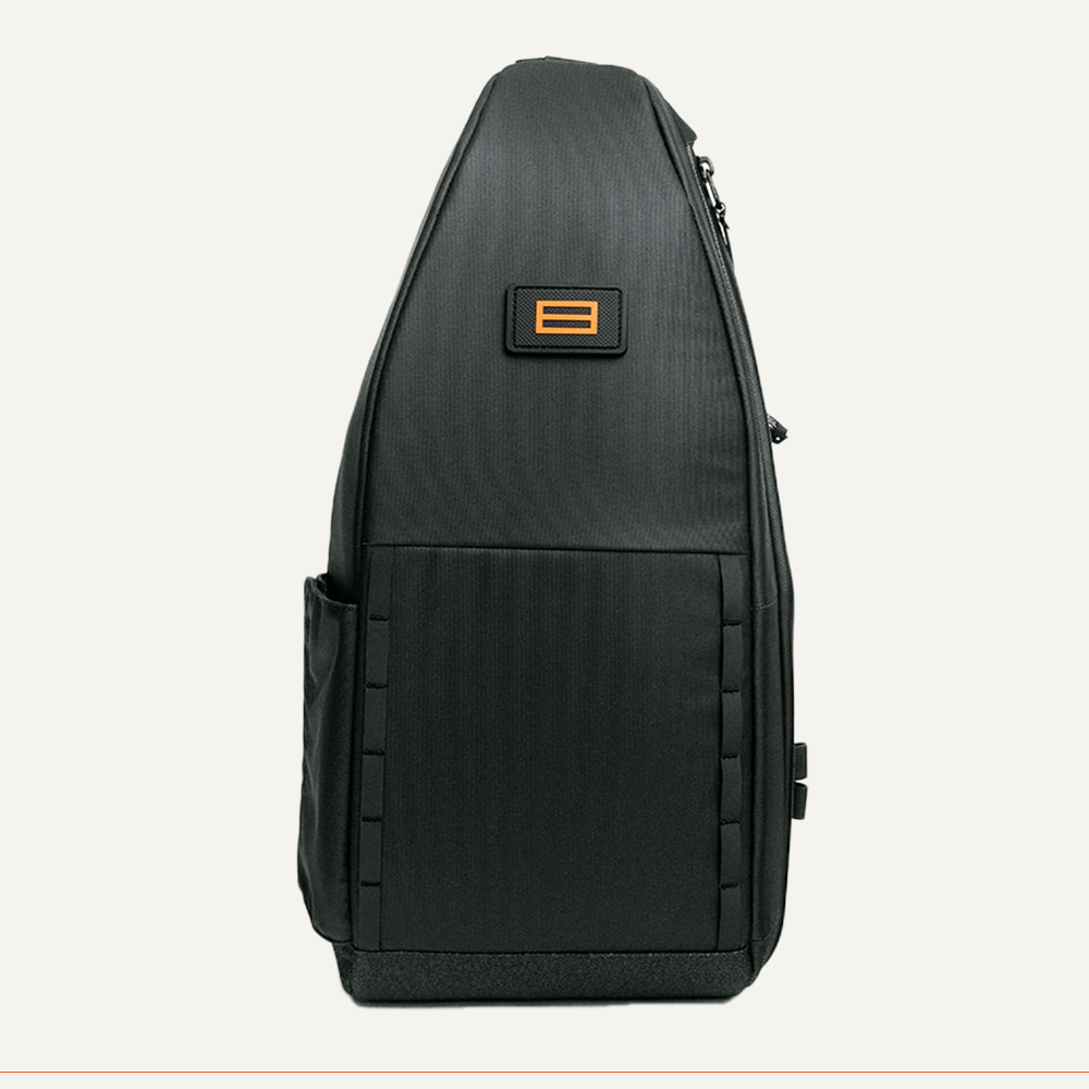 Black sling bag with orange logo patch.