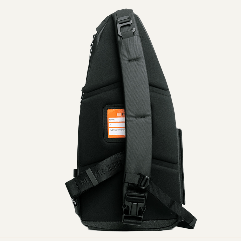 Black padded pickleball sling by FORWRD, side view, with an orange emergency contact label and a strap printed "NEVER SETTLE."