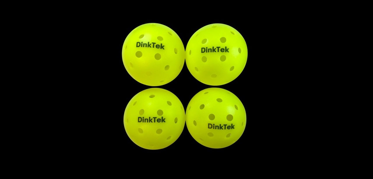 Four yellow DinkTek balls on a black background