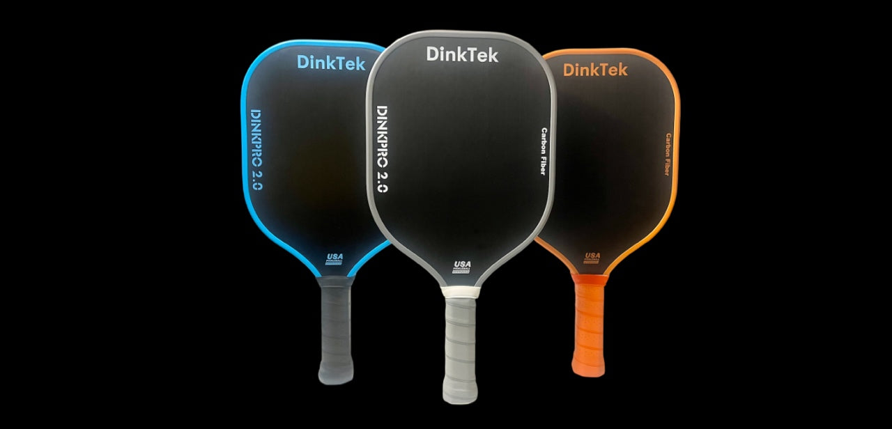 Three DinkTek pickleball paddles in blue, black, and orange on a black background