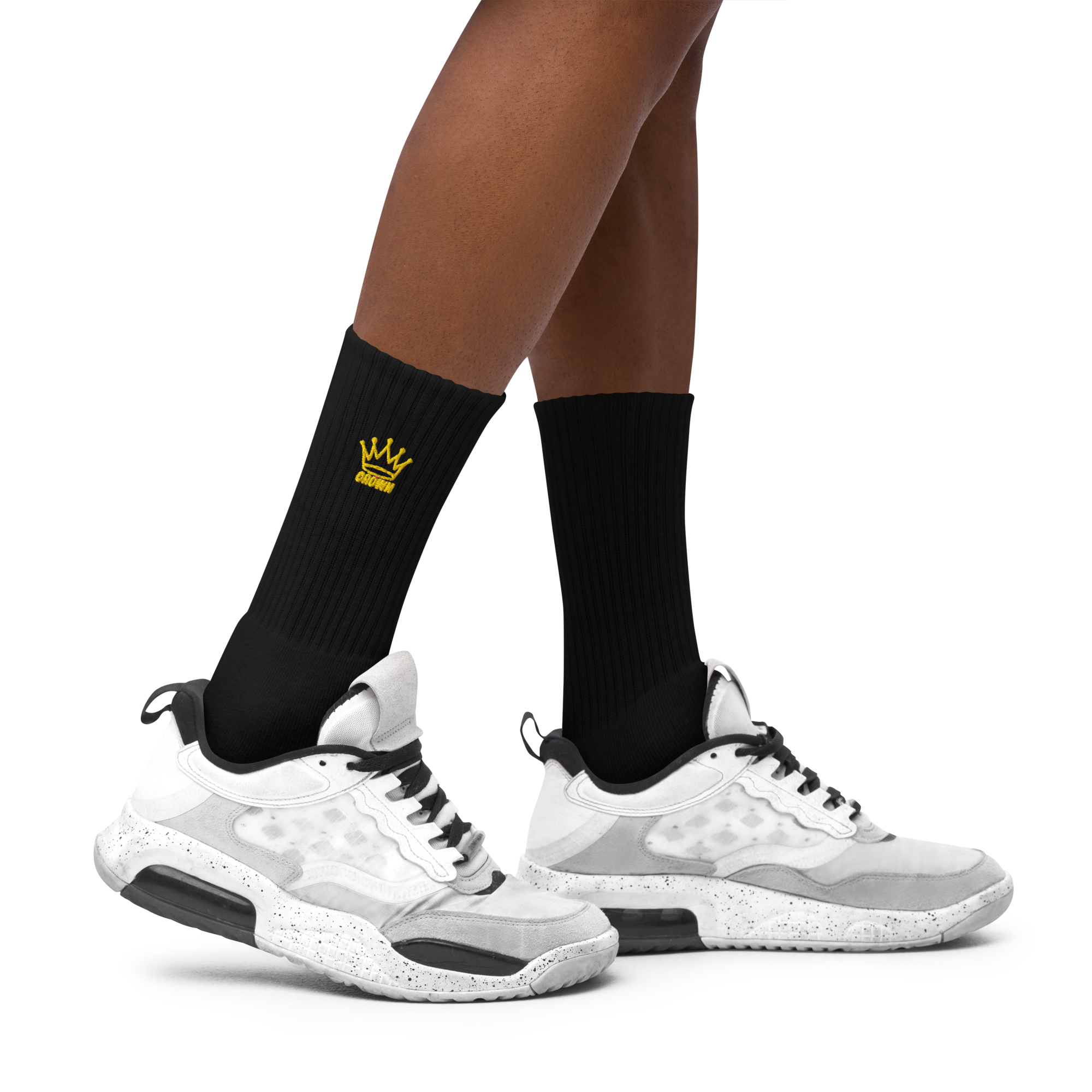 Person wearing black ribbed socks with a yellow crown design and white sneakers.