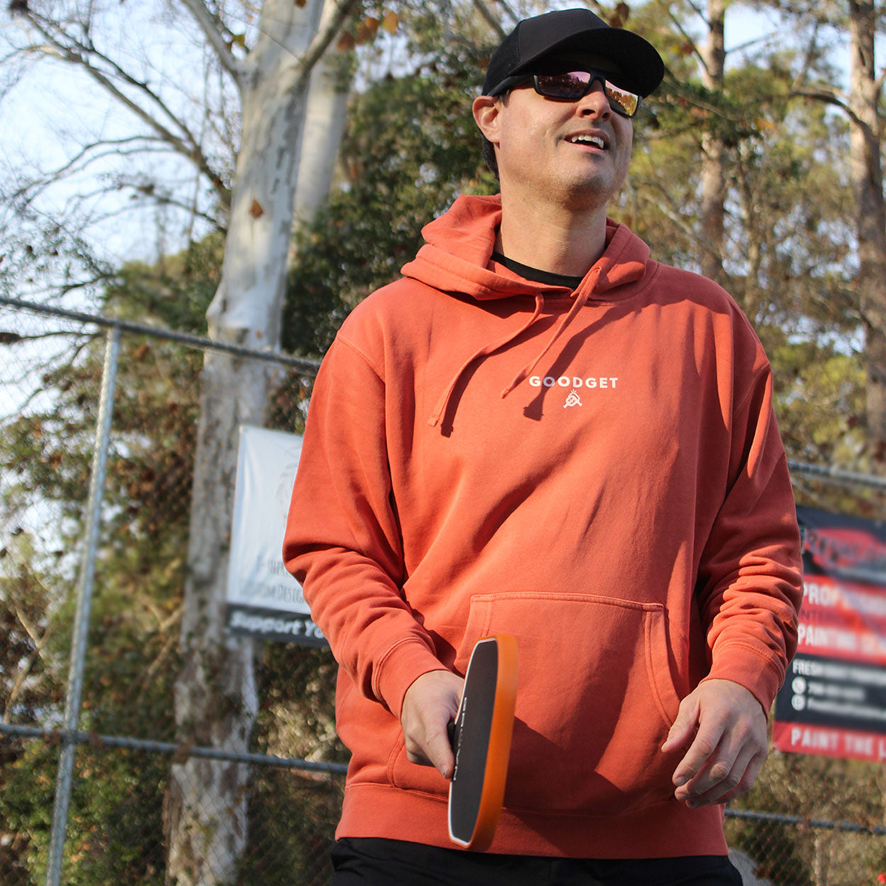 Terracotta hoodie by Good Get, featuring a white chest logo, worn by a man holding a paddle outdoors.