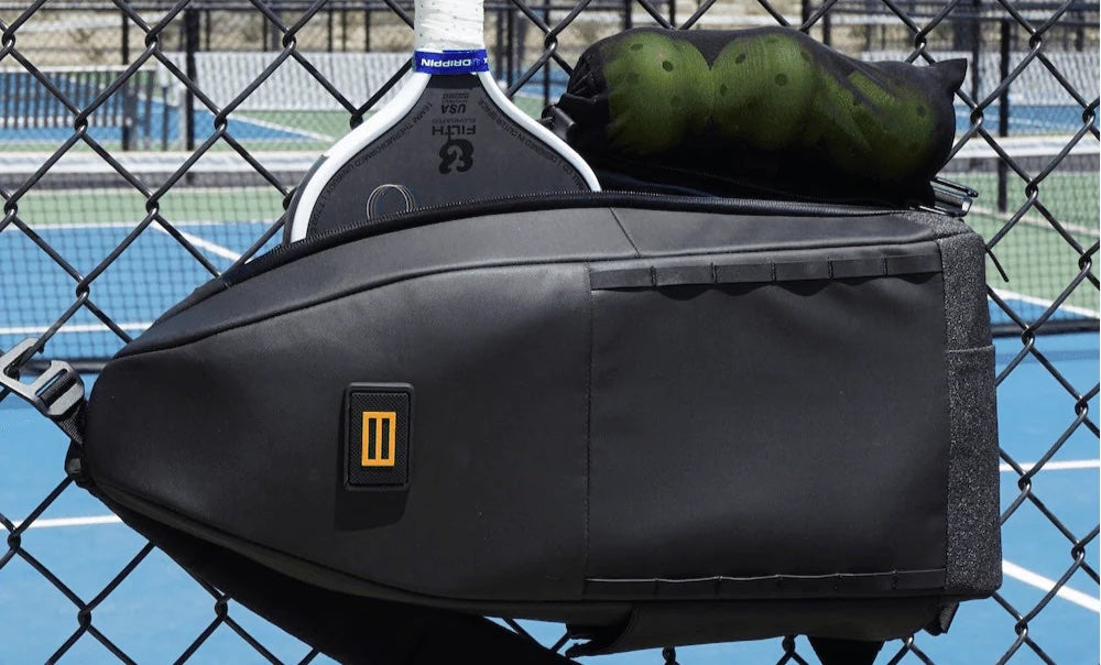 Black tennis bag with a racket and balls on a tennis court
