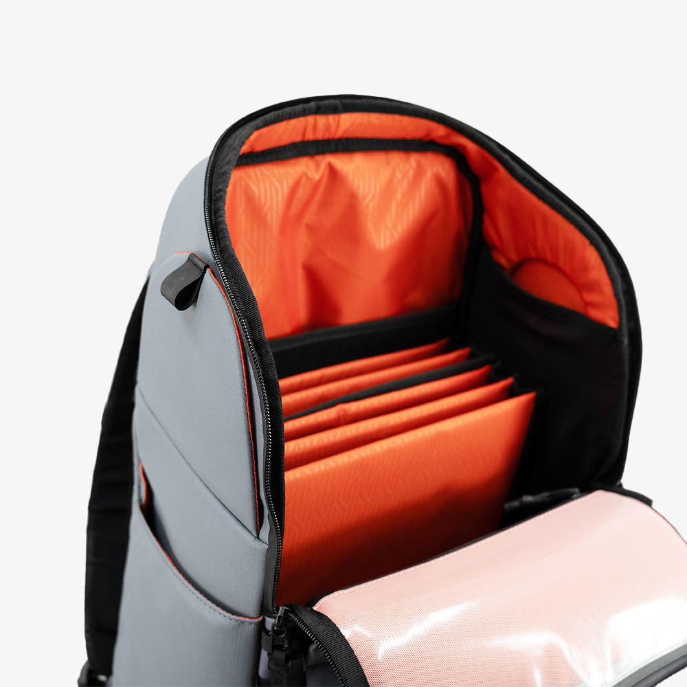 Gray Pickleball Backpack by FORWRD, open to reveal bright orange interior dividers and a clear pink pocket.