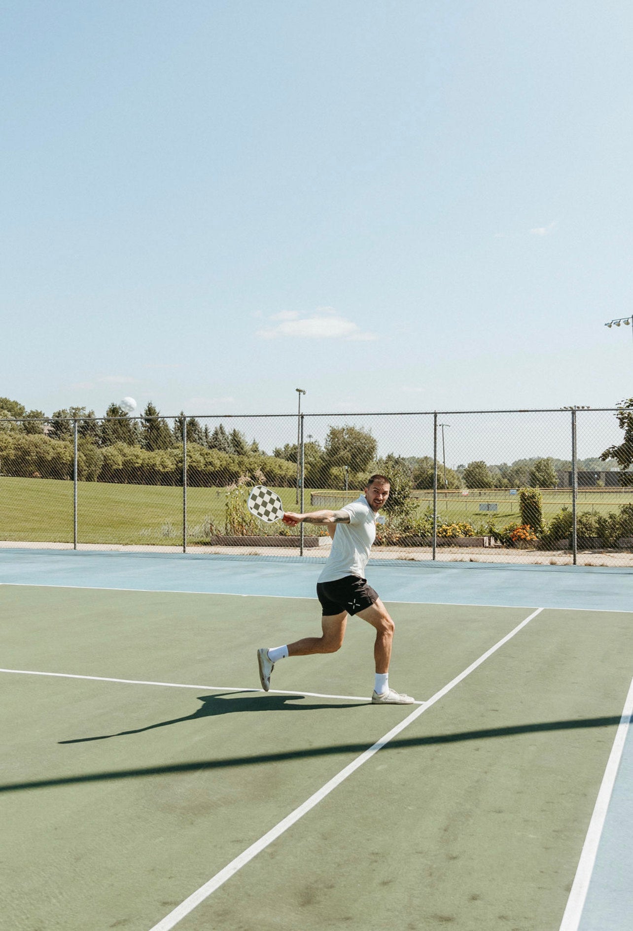 Man in athletic wear playing pickleball on an outdoor court.
