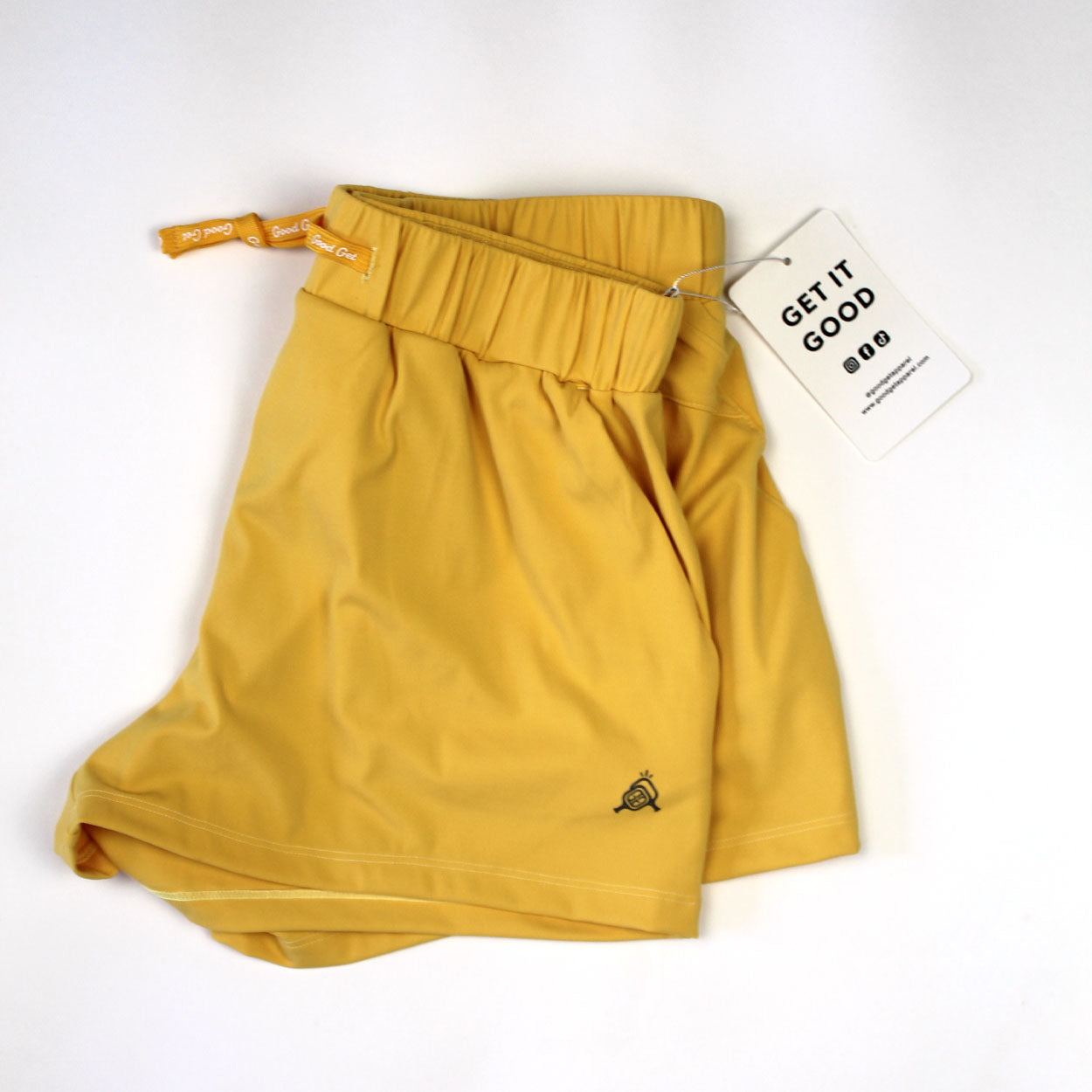 Folded yellow shorts with a drawstring and tag.
