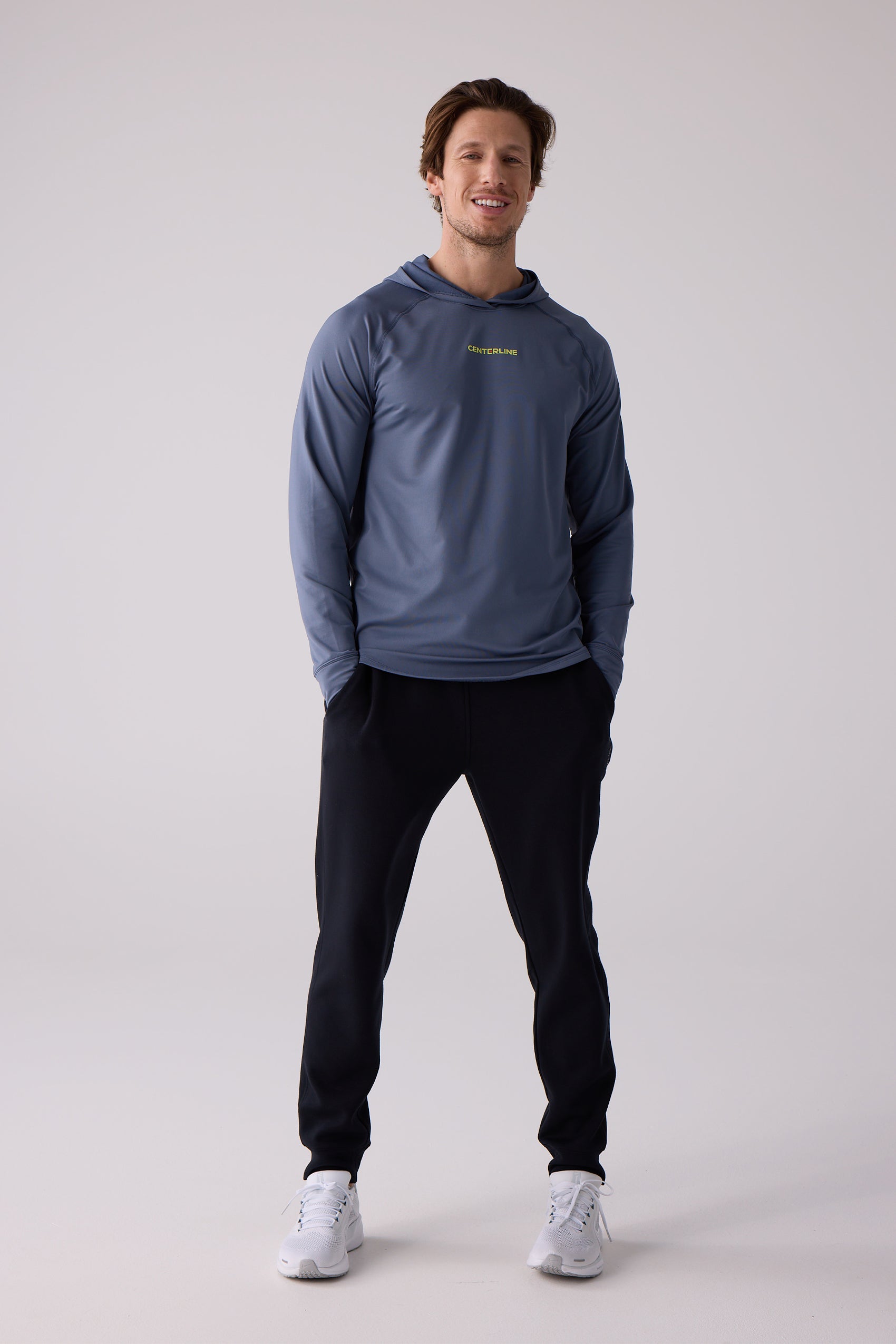 Blue-gray men's layering hoodie by Centerline Athletics with yellow-green text, worn with black pants and white shoes.