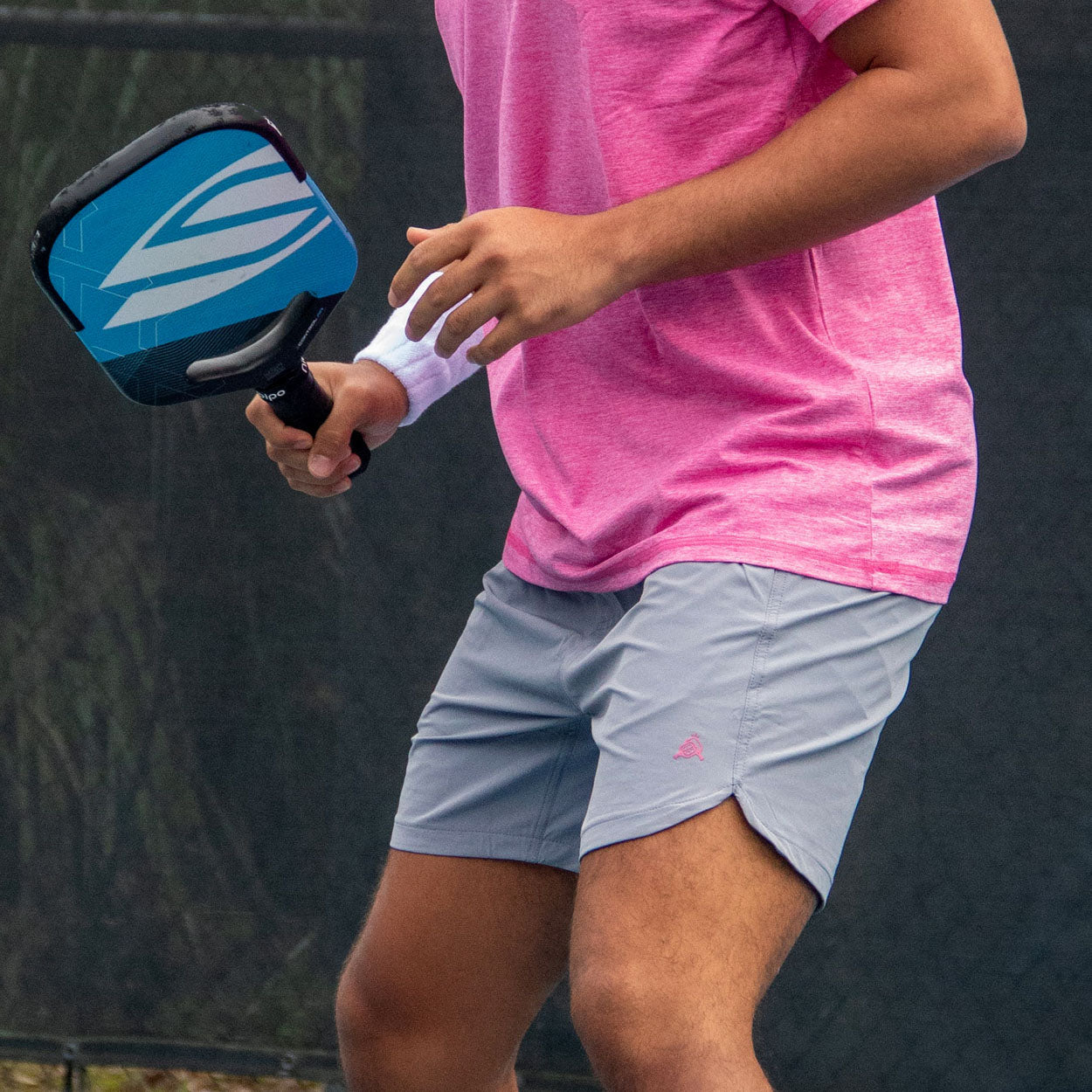 Light grey Pickleball Shorts by Good Get featuring a pink turtle logo, worn with a pink shirt while holding a blue pickleball paddle.