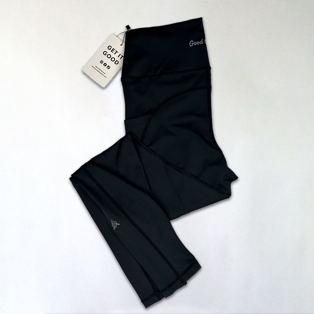 Black leggings with tag on a white surface.