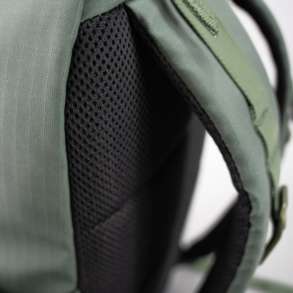 Close-up of a green backpack with black mesh padding.