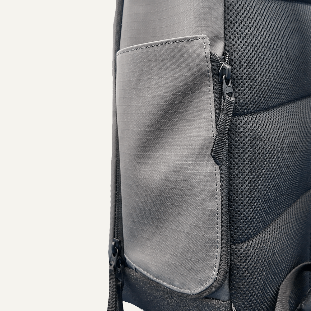 Close-up of a grey and black backpack with a front pocket and zipper.