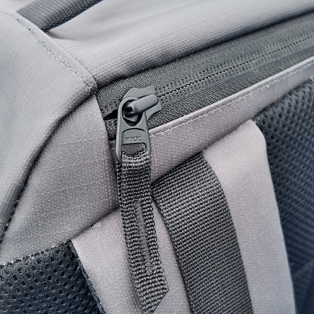 Close-up of a gray backpack with a black YKK zipper.