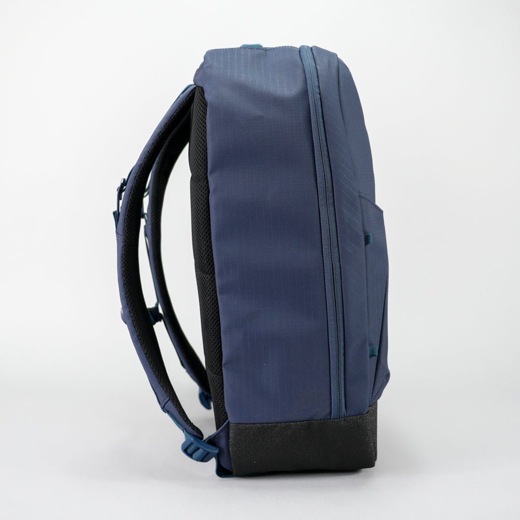 Dark blue pickleball backpack by FORWRD, side view showing padded straps, ripstop fabric, and a black base.