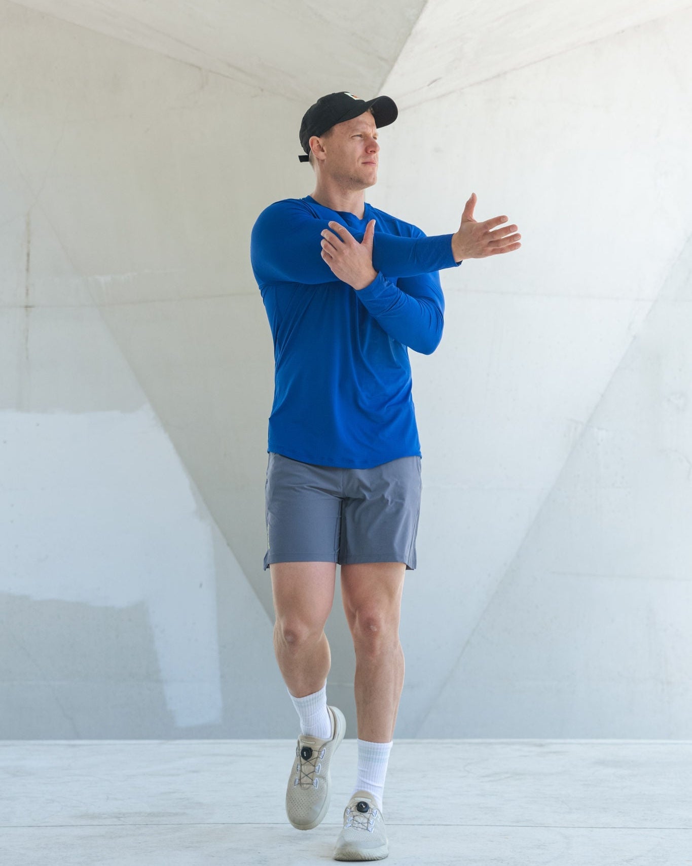 Man in blue shirt and gray shorts stretching.