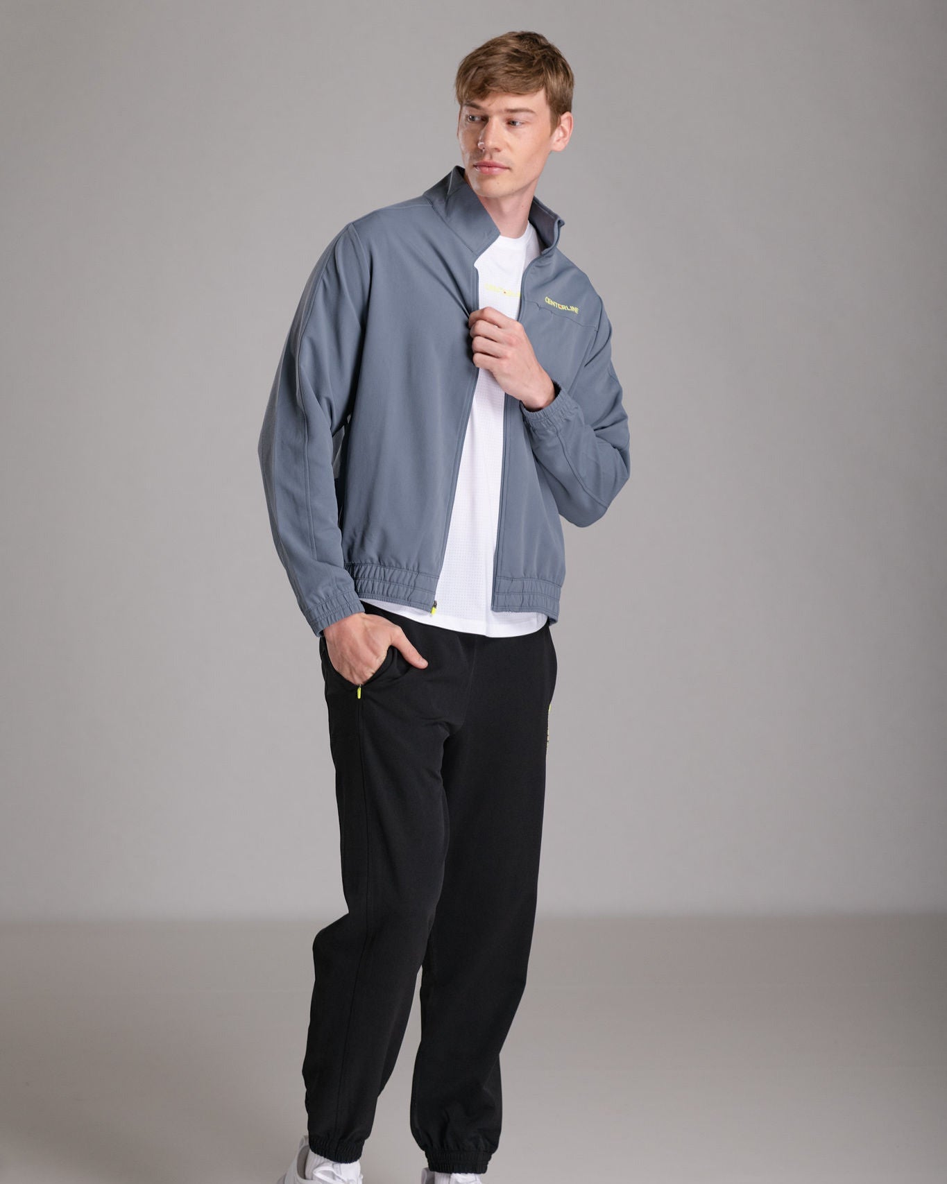 Man in gray jacket, white t-shirt, and black pants.