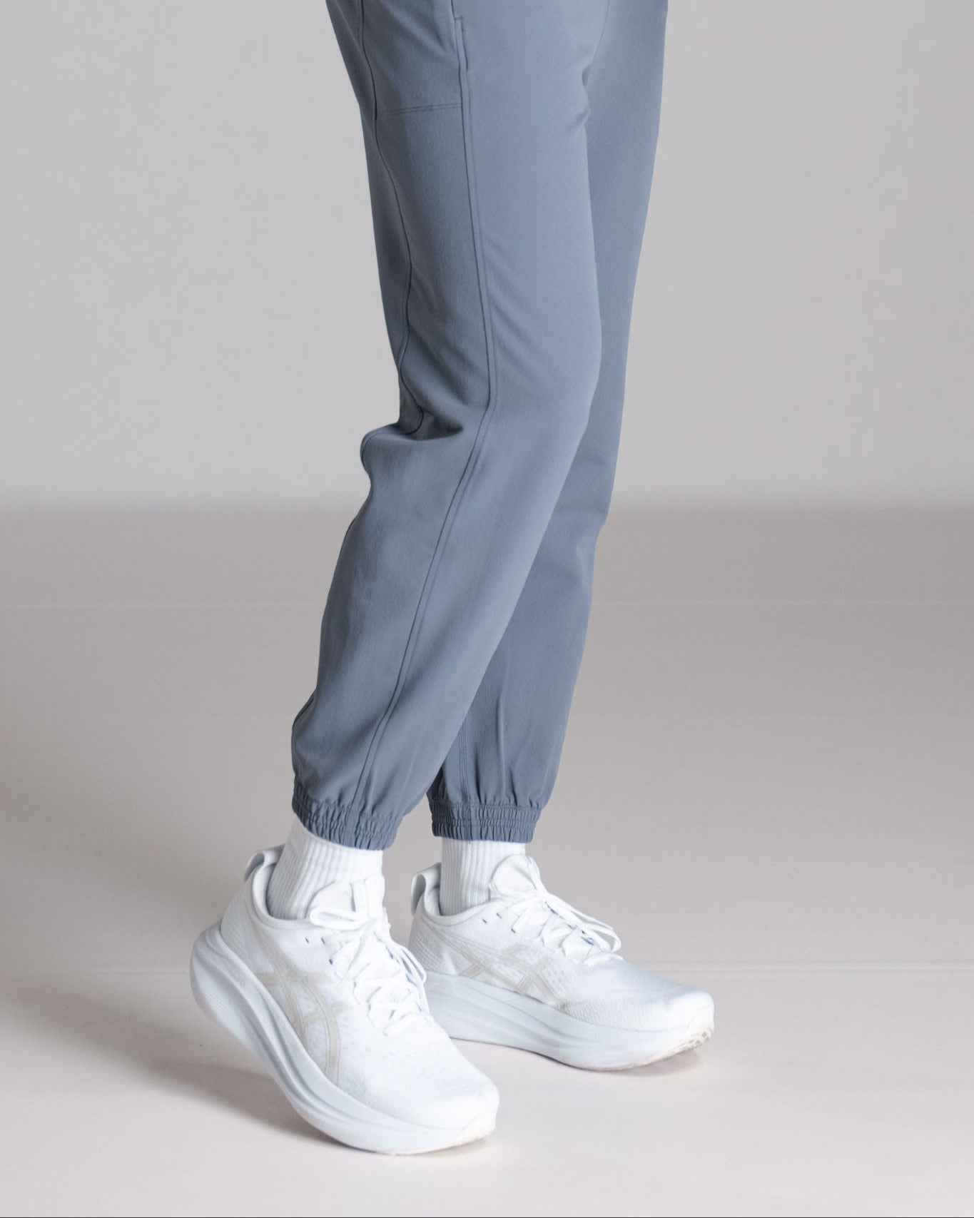 Person wearing blue jogger pants and white running shoes.