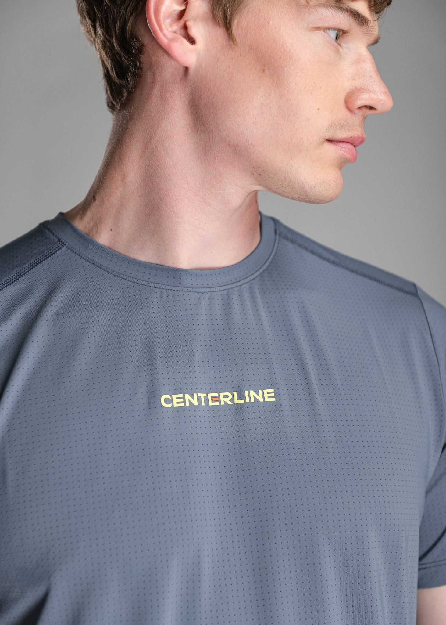 Man in a gray perforated T-shirt with yellow "CENTERLINE" text.