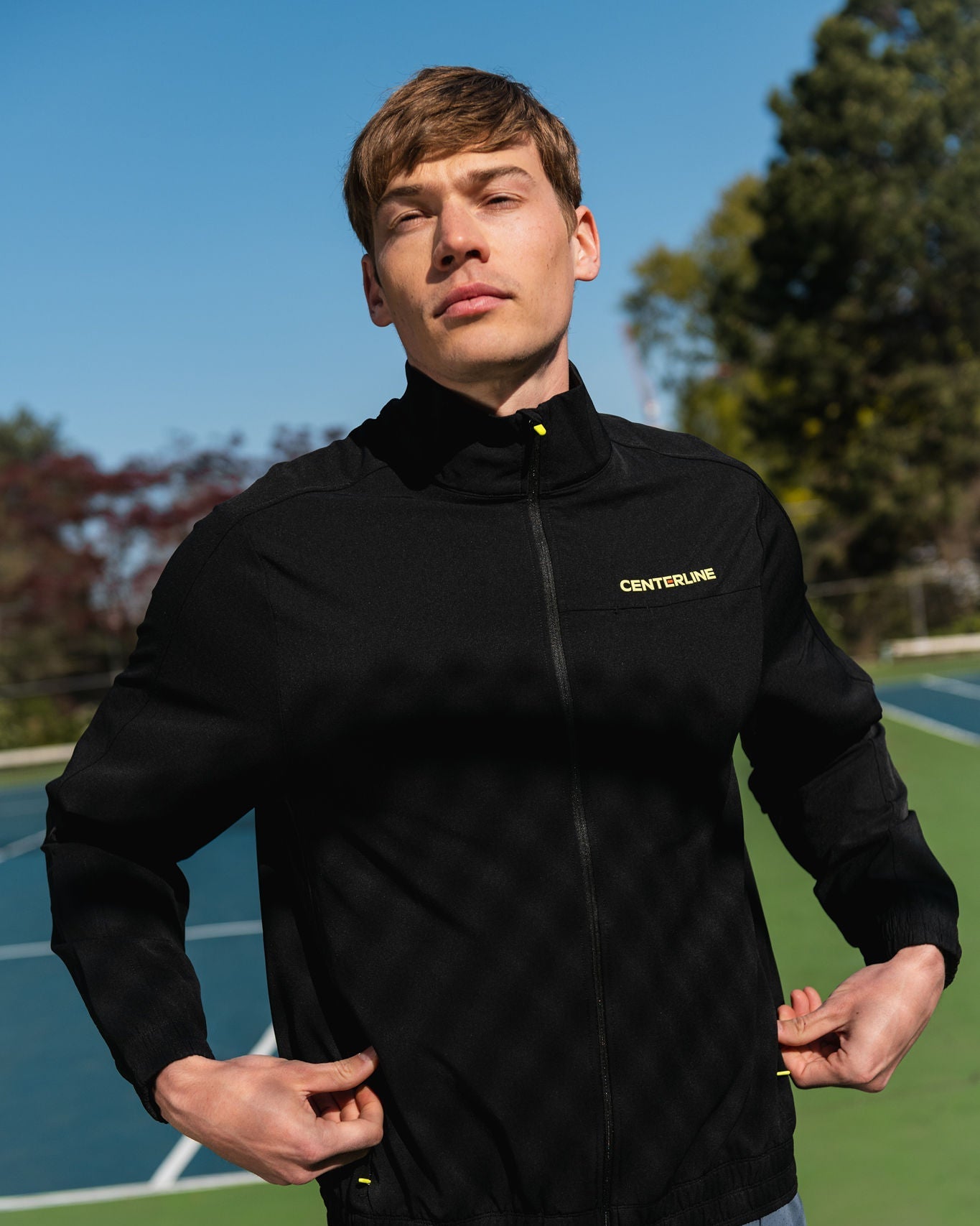 Man in black Centerline jacket on a tennis court.