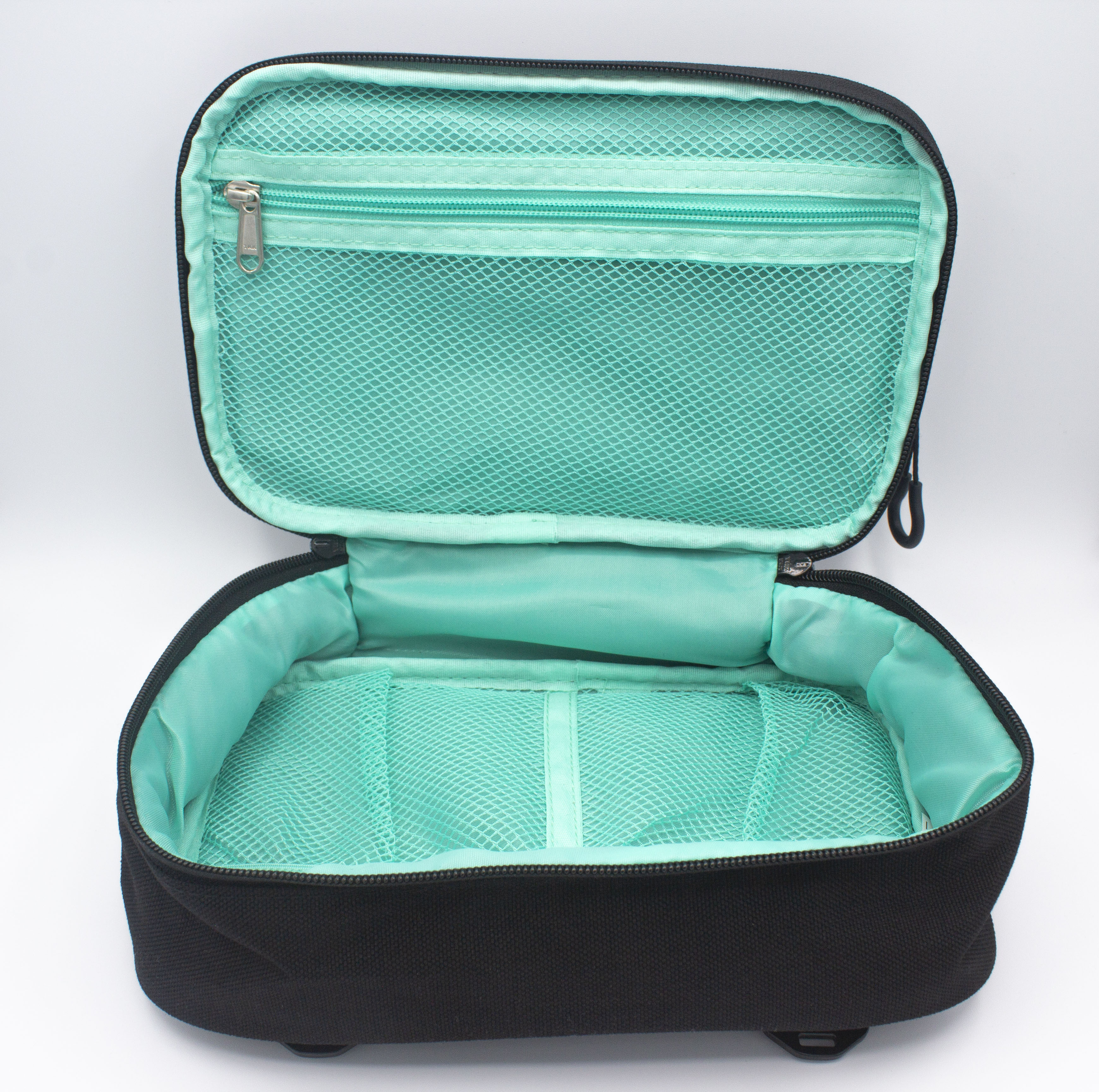 Black fabric Accessory Case by Bodhi Performance, open to reveal a bright teal interior with diamond mesh pockets and a zippered compartment.