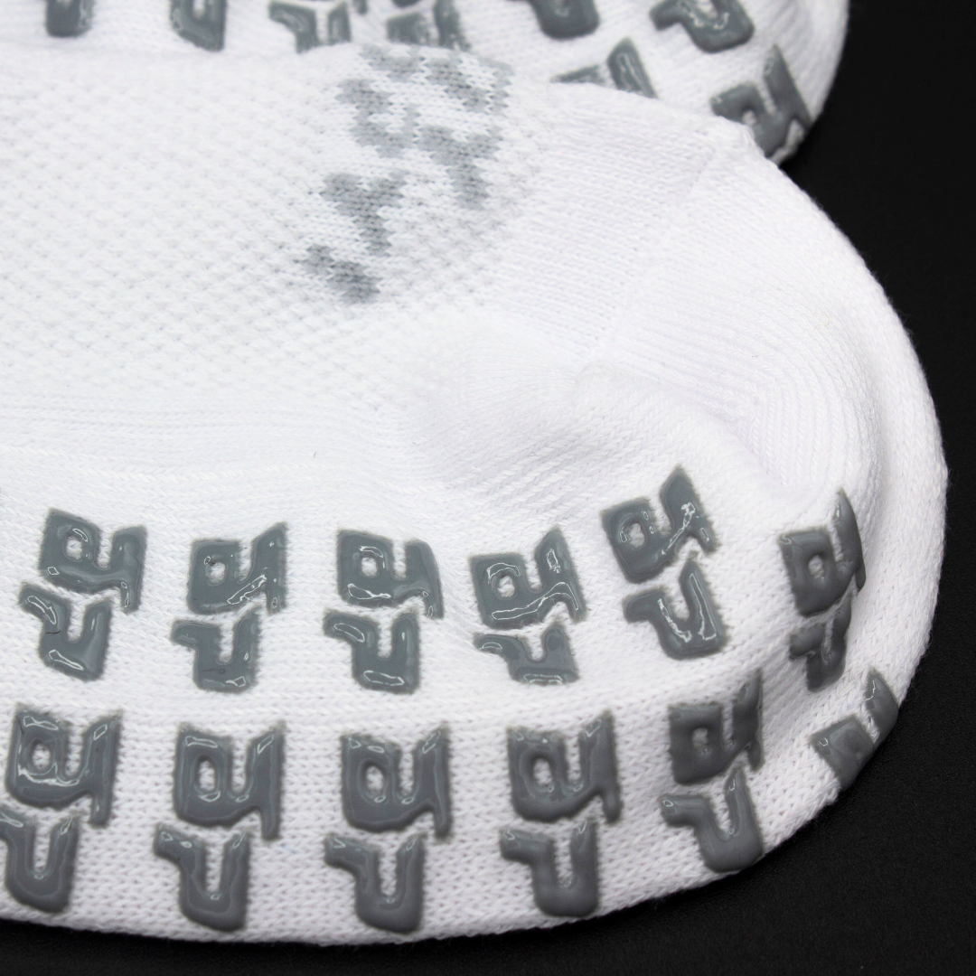 White Performance Socks from Bodhi Performance with grey GRIPtech™ anti-slip grips on the sole and a textured knit upper.