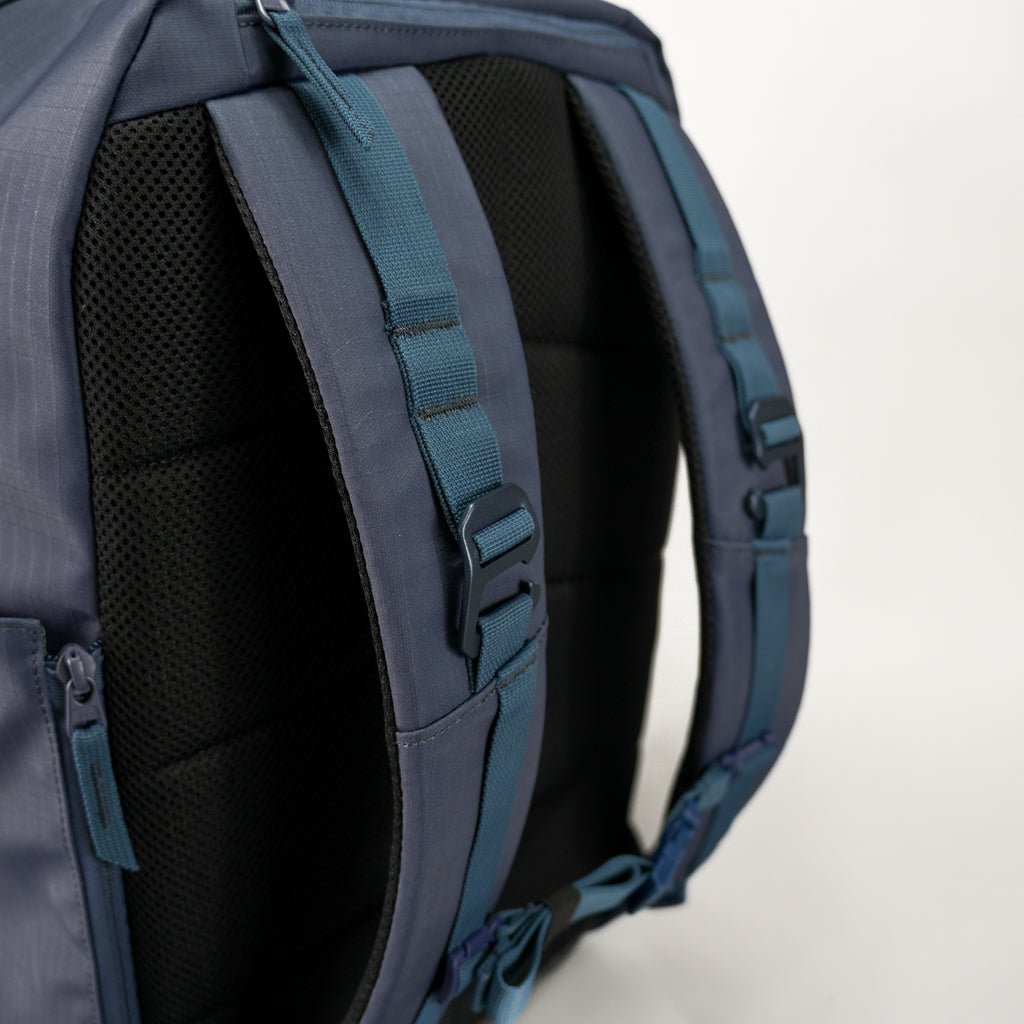 Close-up of a blue backpack's back, featuring mesh padding and adjustable straps.