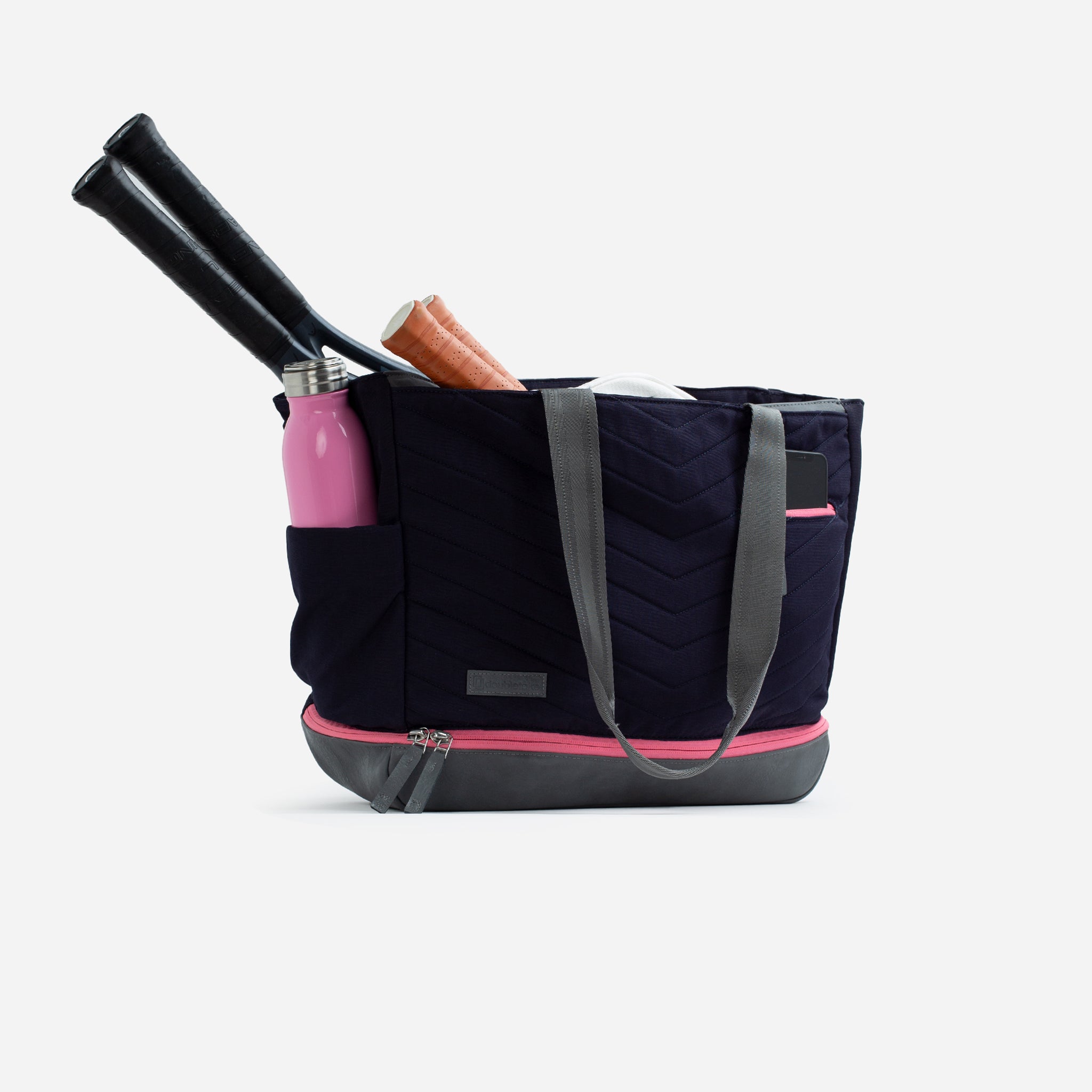 Navy blue quilted Pickleball Tote by Doubletake with pink trim, grey straps, and side pockets holding rackets, a water bottle, and a phone.